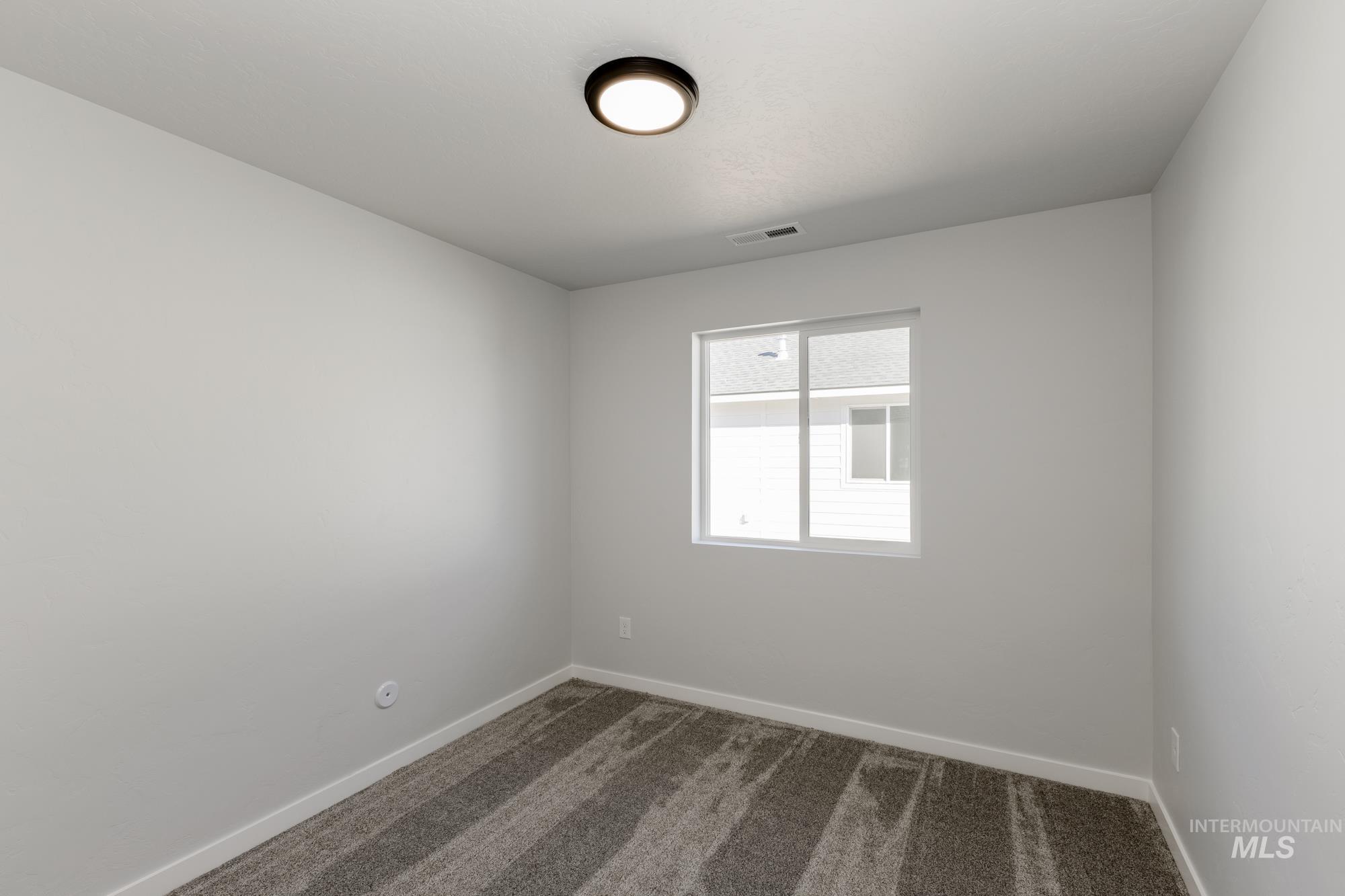 Empty room with dark colored carpet and baseboards