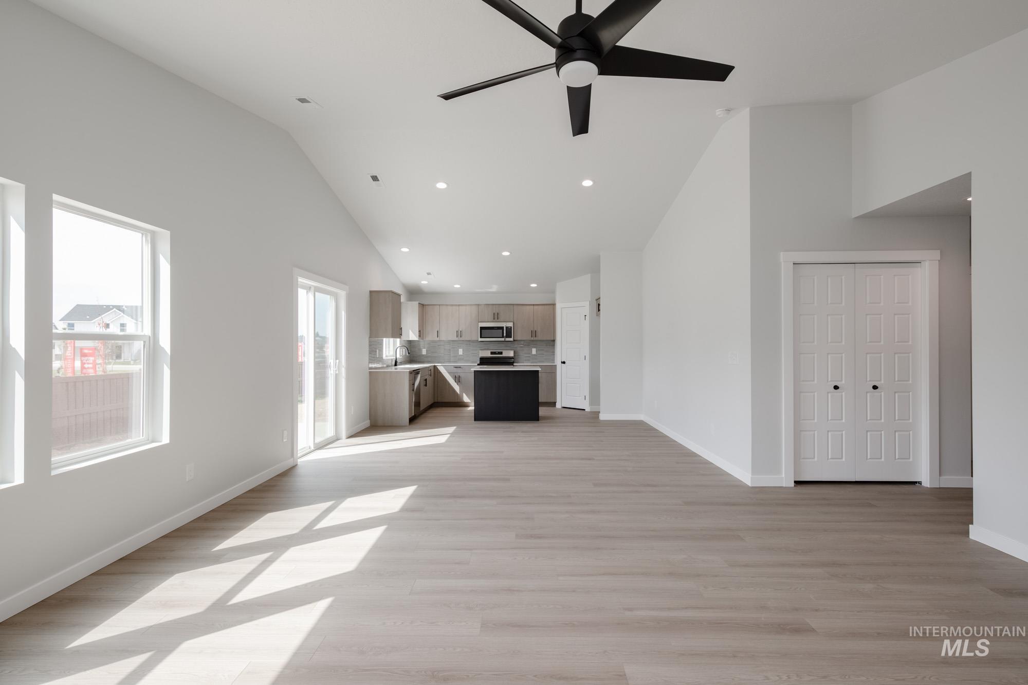 Unfurnished living room featuring light wood-type flooring, recessed lighting, high vaulted ceiling, and a ceiling fan