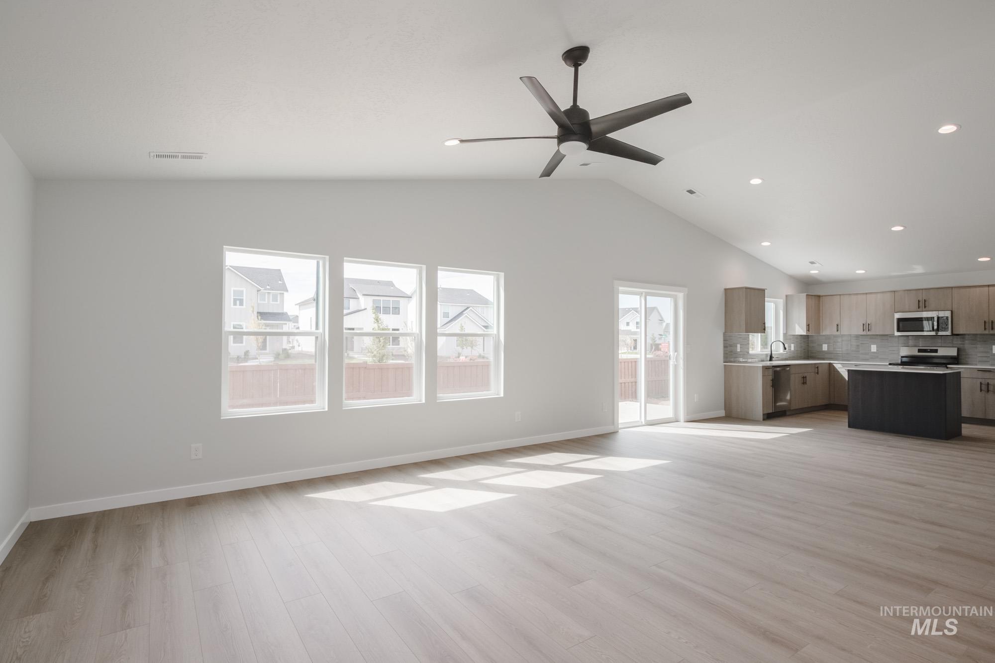 Unfurnished living room with light wood-type flooring, lofted ceiling, recessed lighting, and ceiling fan