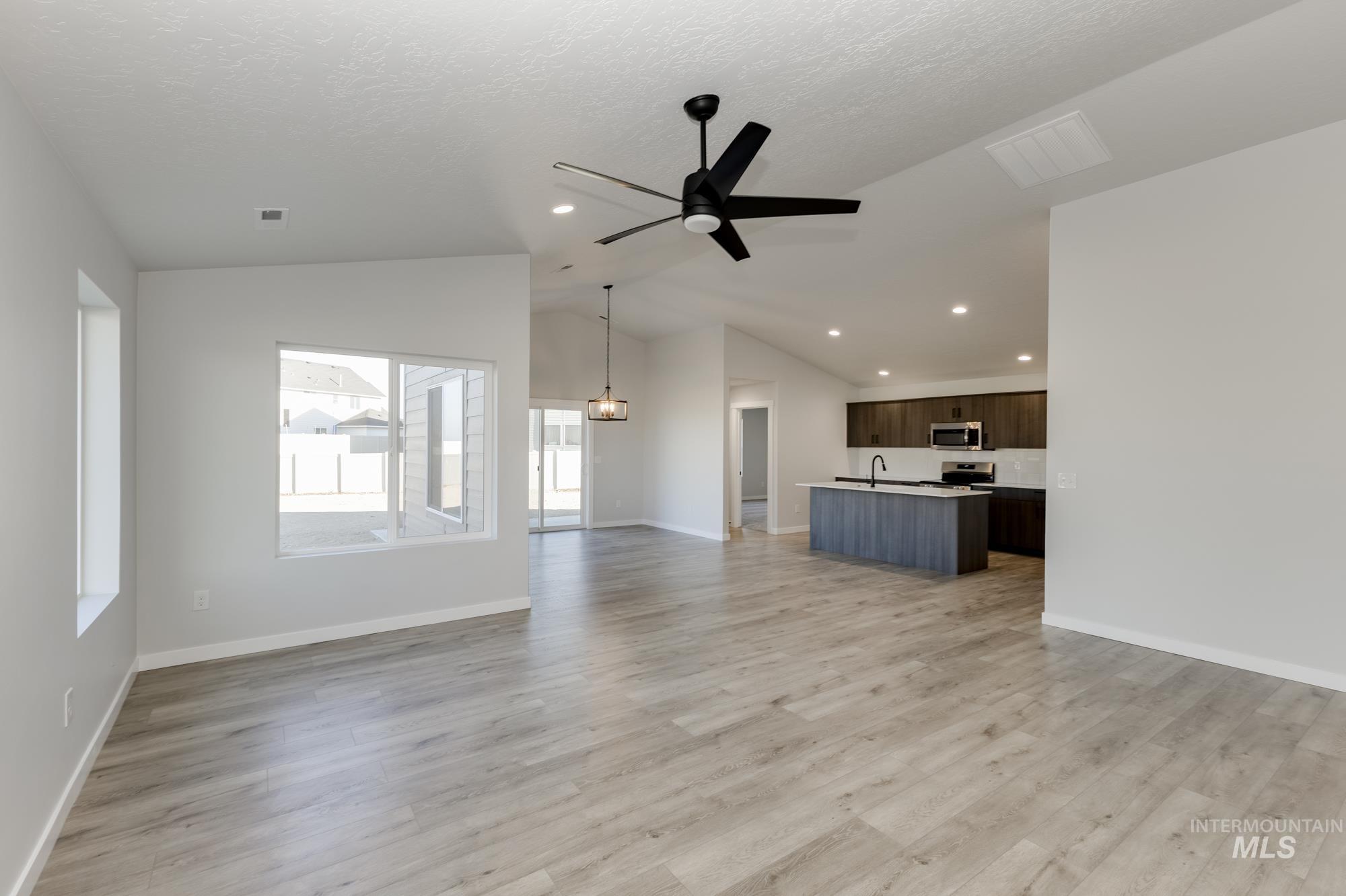 Unfurnished living room featuring light wood-style flooring, lofted ceiling, a ceiling fan, recessed lighting, and a textured ceiling
