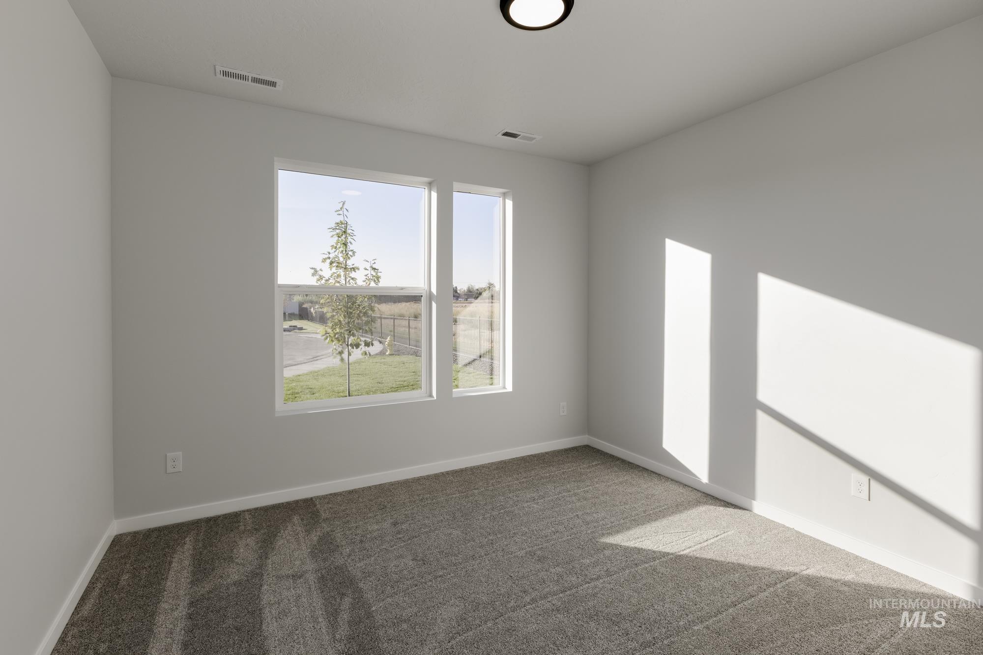 Carpeted spare room featuring baseboards