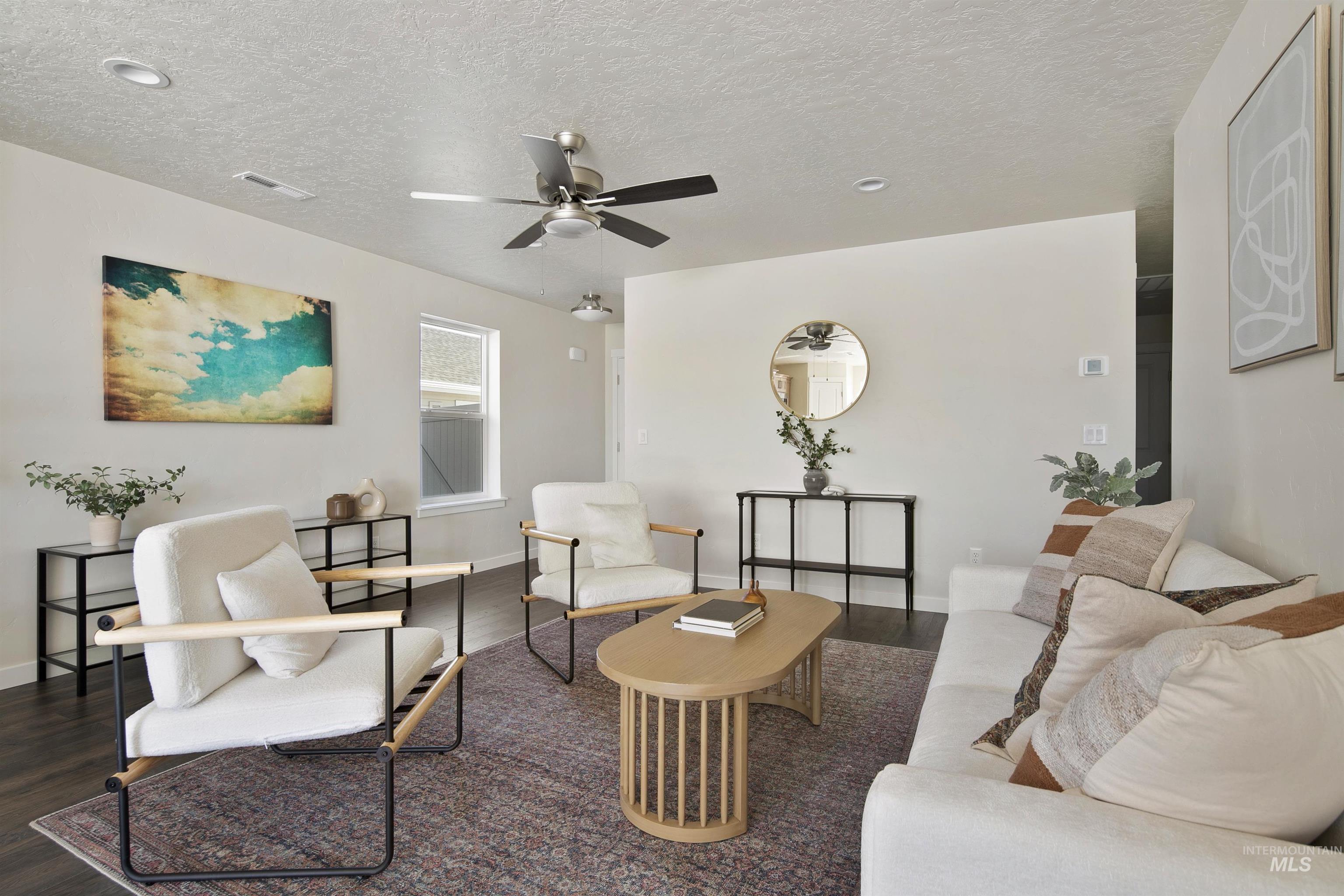 Living room featuring dark wood-type flooring, a textured ceiling, and ceiling fan