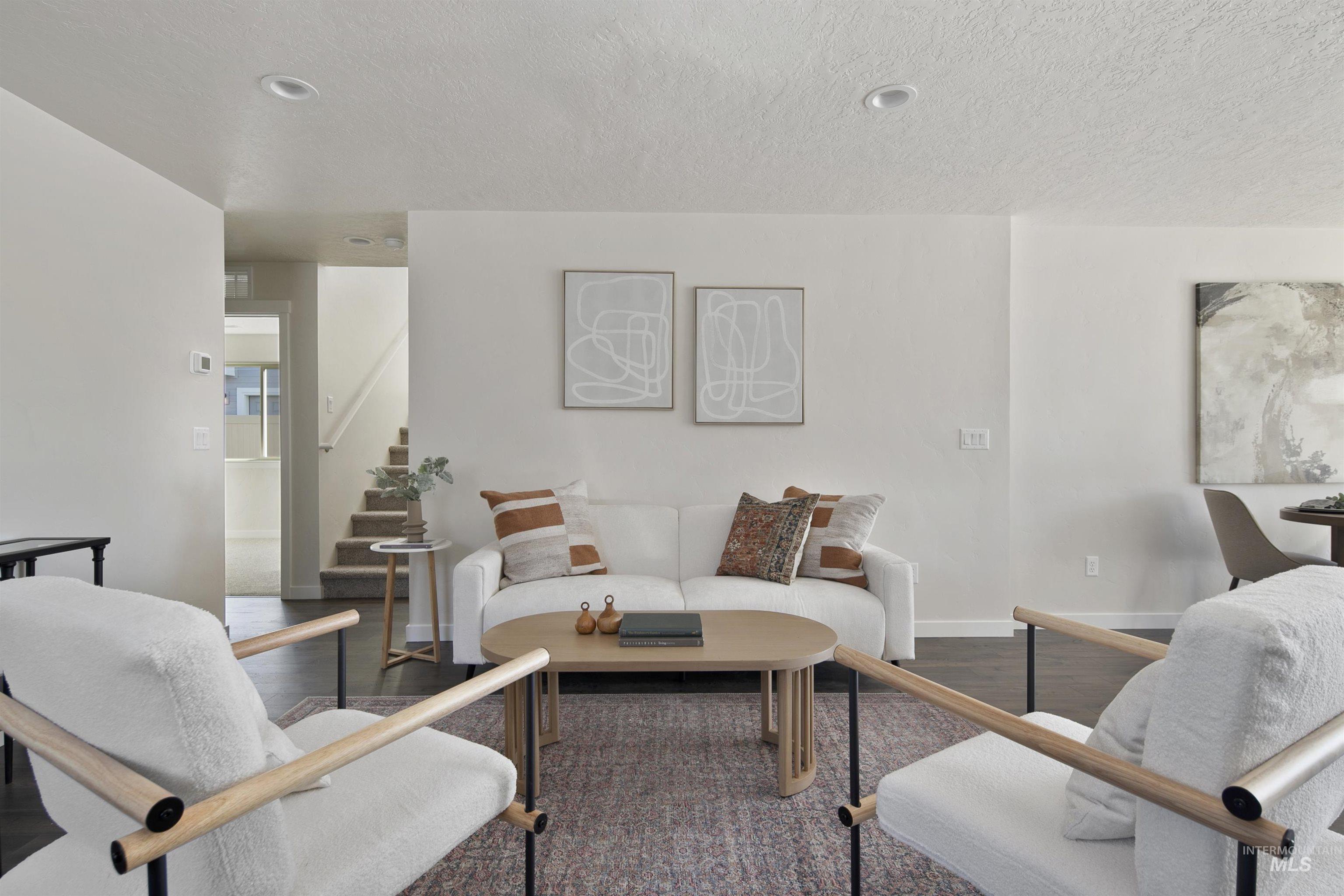 Living area with wood finished floors, a textured ceiling, and stairs