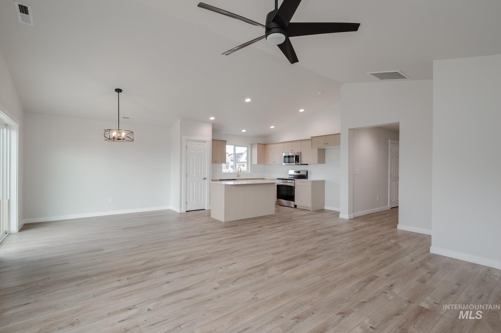 Unfurnished living room featuring lofted ceiling, light wood-type flooring, recessed lighting, ceiling fan, and a chandelier