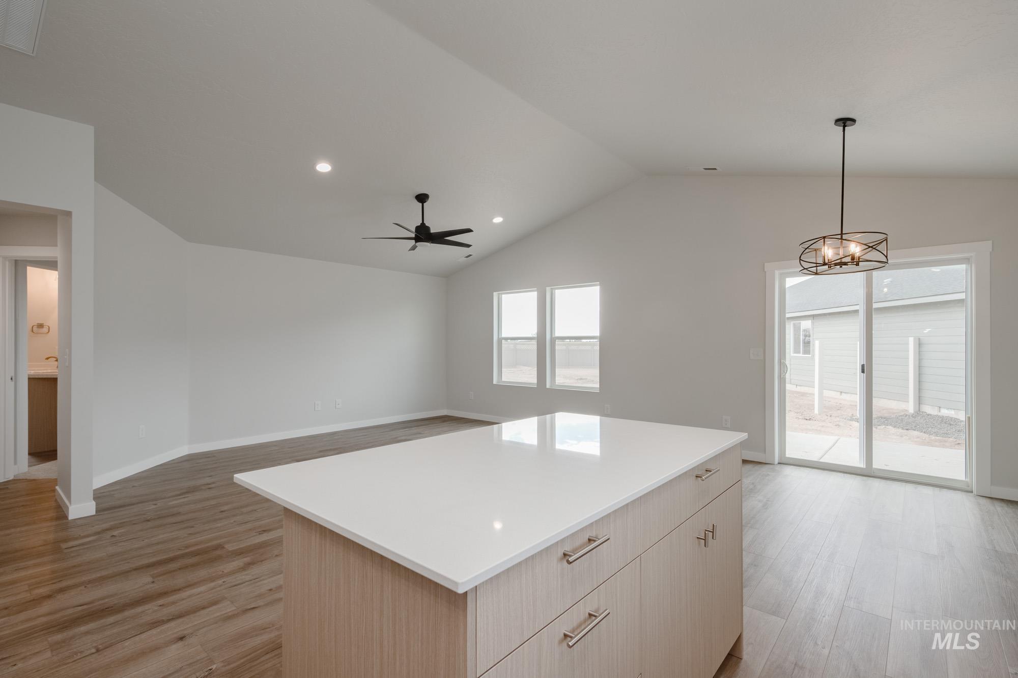 Kitchen with light wood-type flooring, pendant lighting, recessed lighting, lofted ceiling, and a center island
