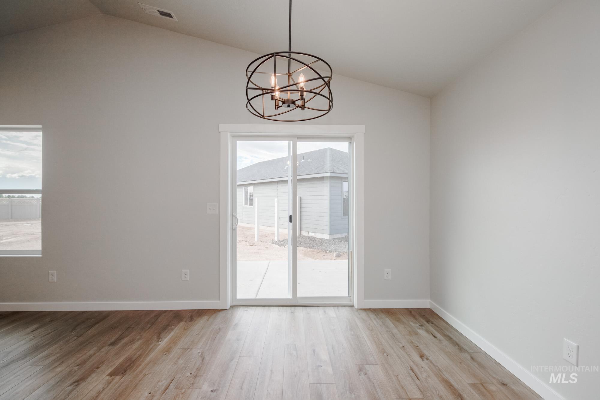 Unfurnished dining area featuring light wood-type flooring, vaulted ceiling, and a chandelier