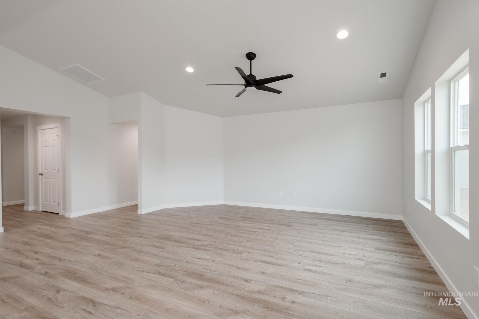 Empty room with light wood-style floors, recessed lighting, ceiling fan, and vaulted ceiling