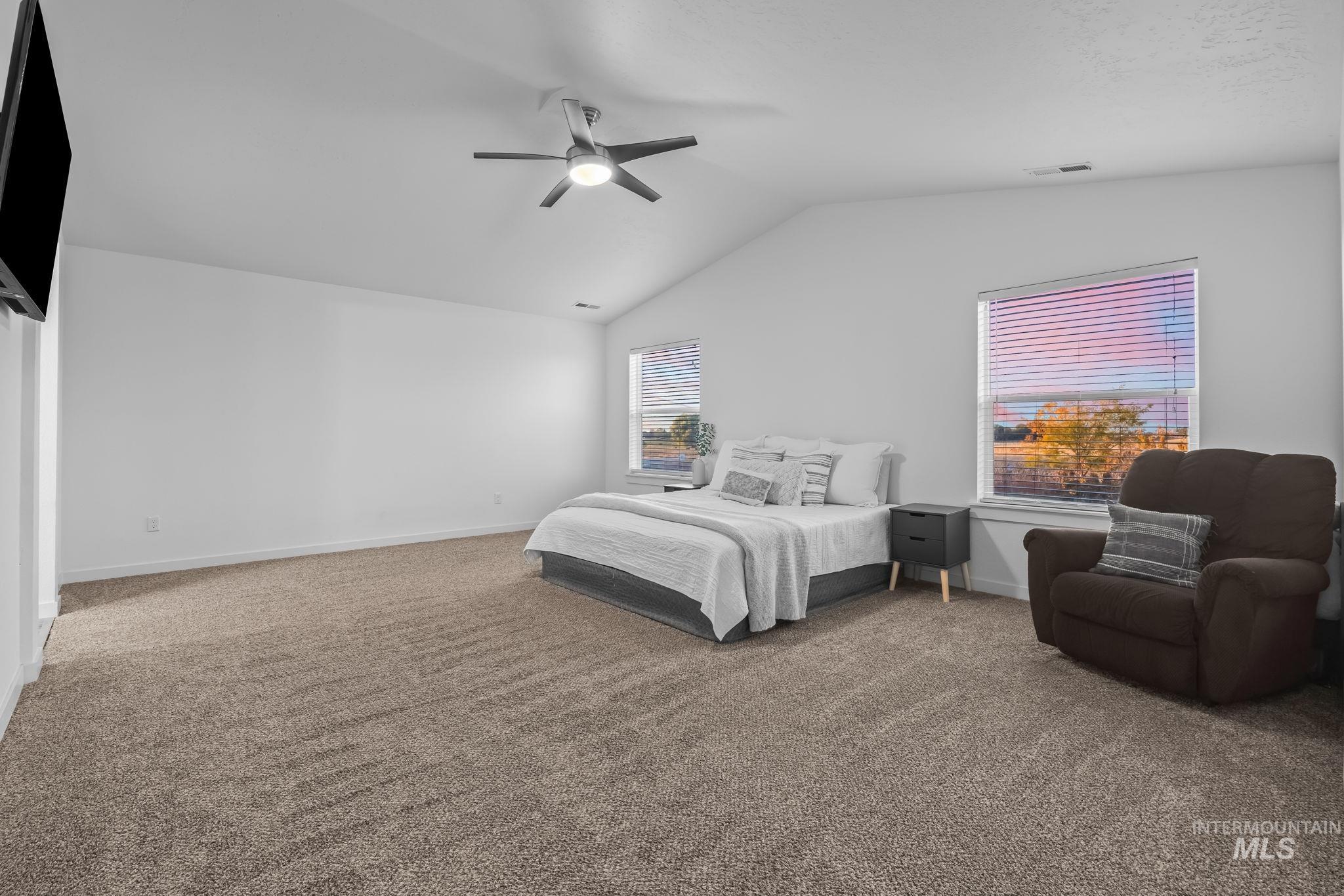 Bedroom with light carpet, vaulted ceiling, and ceiling fan