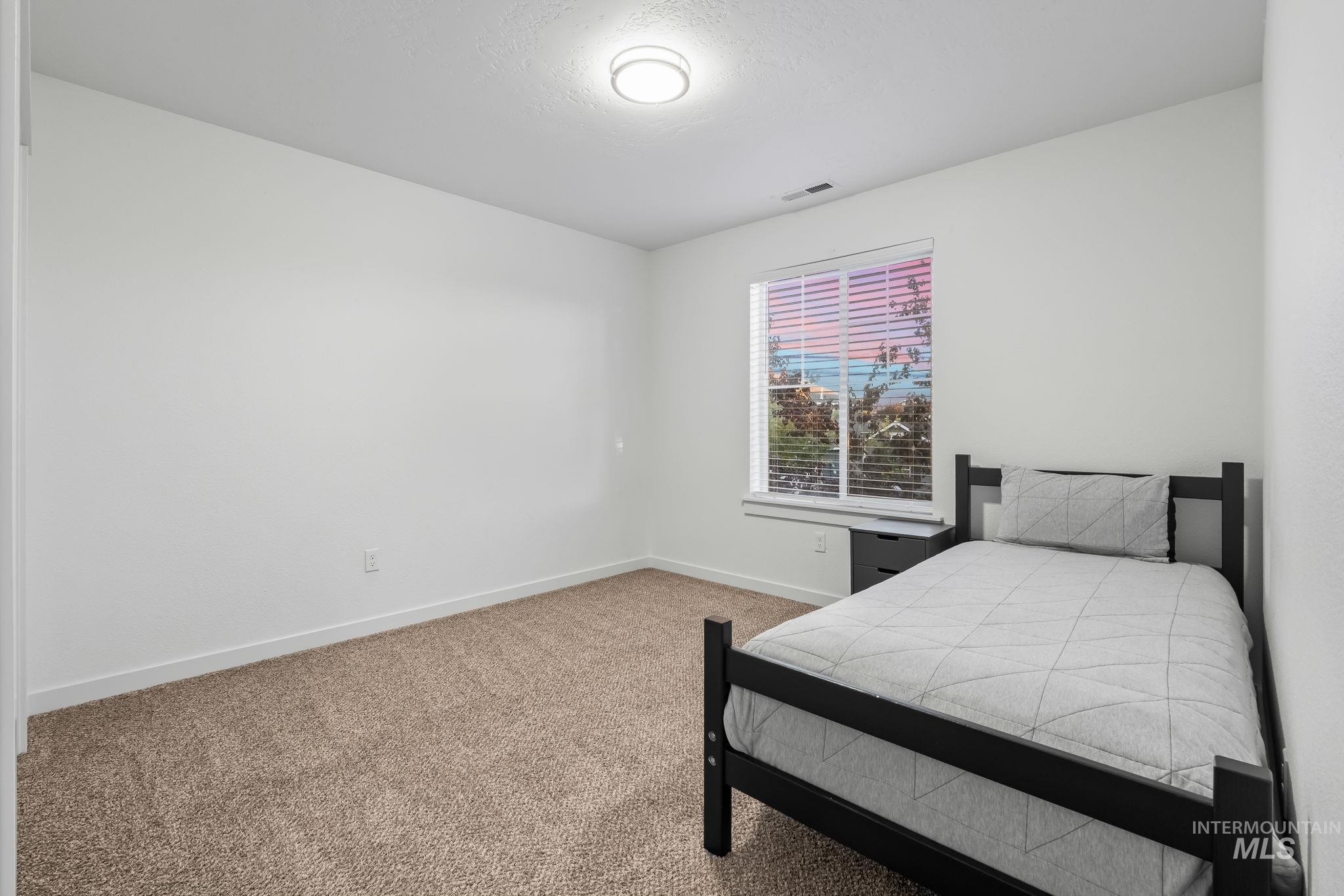 Carpeted bedroom with baseboards and a textured ceiling