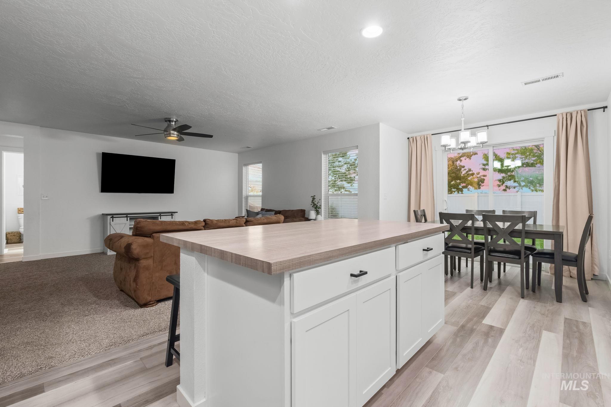 Kitchen featuring a kitchen island, open floor plan, white cabinetry, a breakfast bar, and a textured ceiling