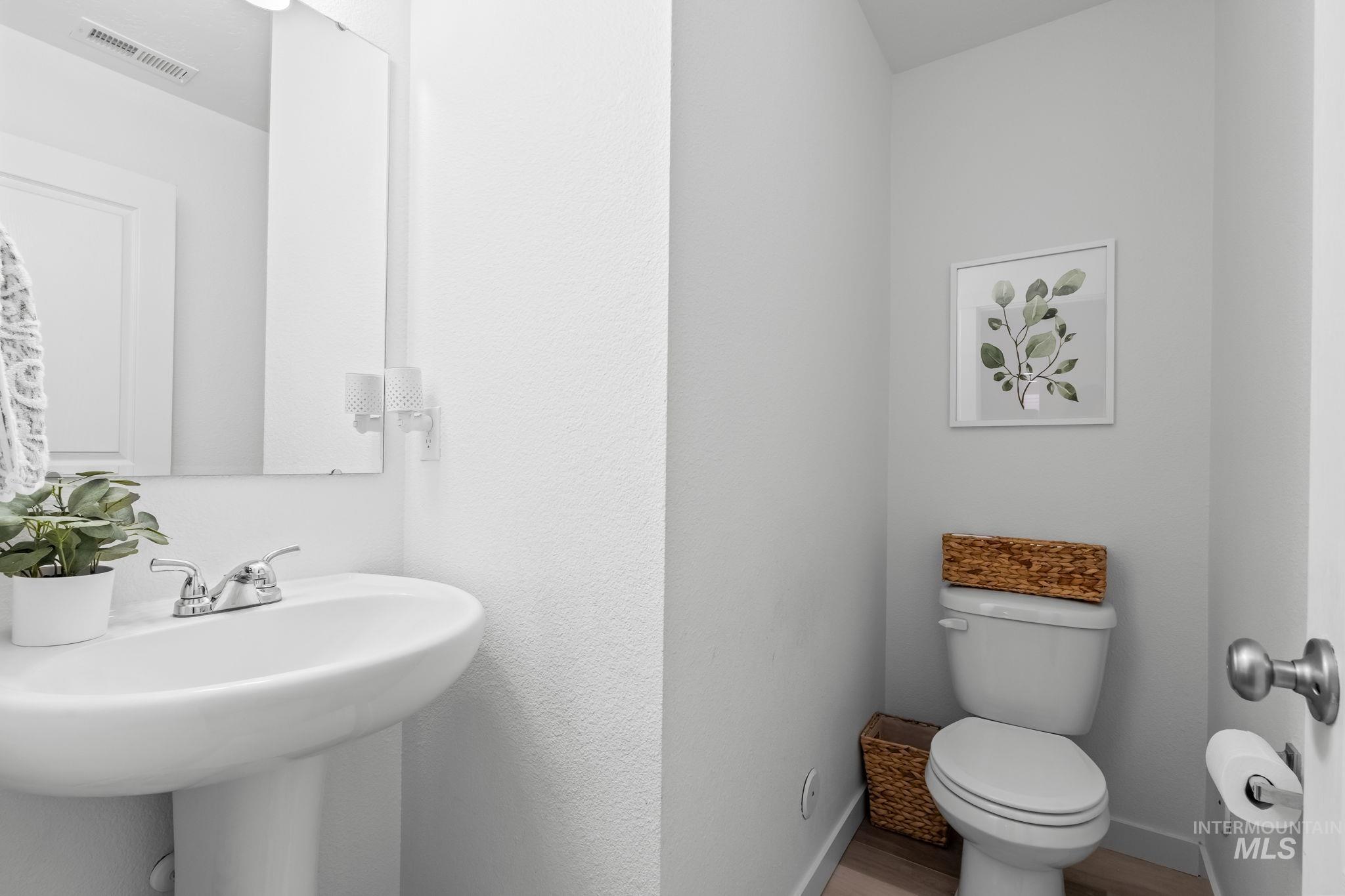 Half bathroom featuring toilet and wood finished floors