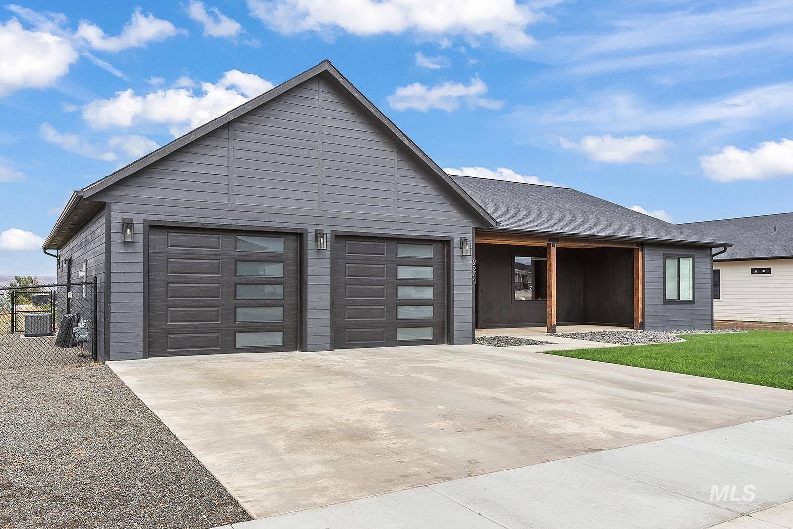 View of front of house featuring driveway, covered porch, and an attached garage