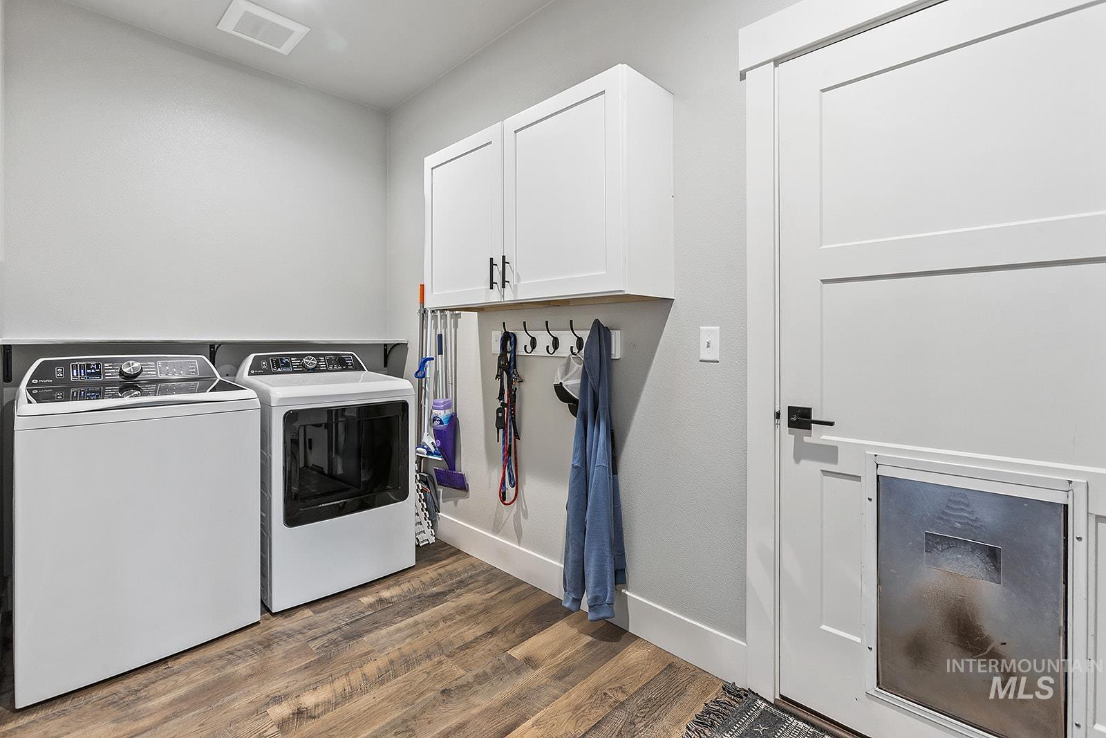 Laundry area with dark wood finished floors, cabinet space, and independent washer and dryer