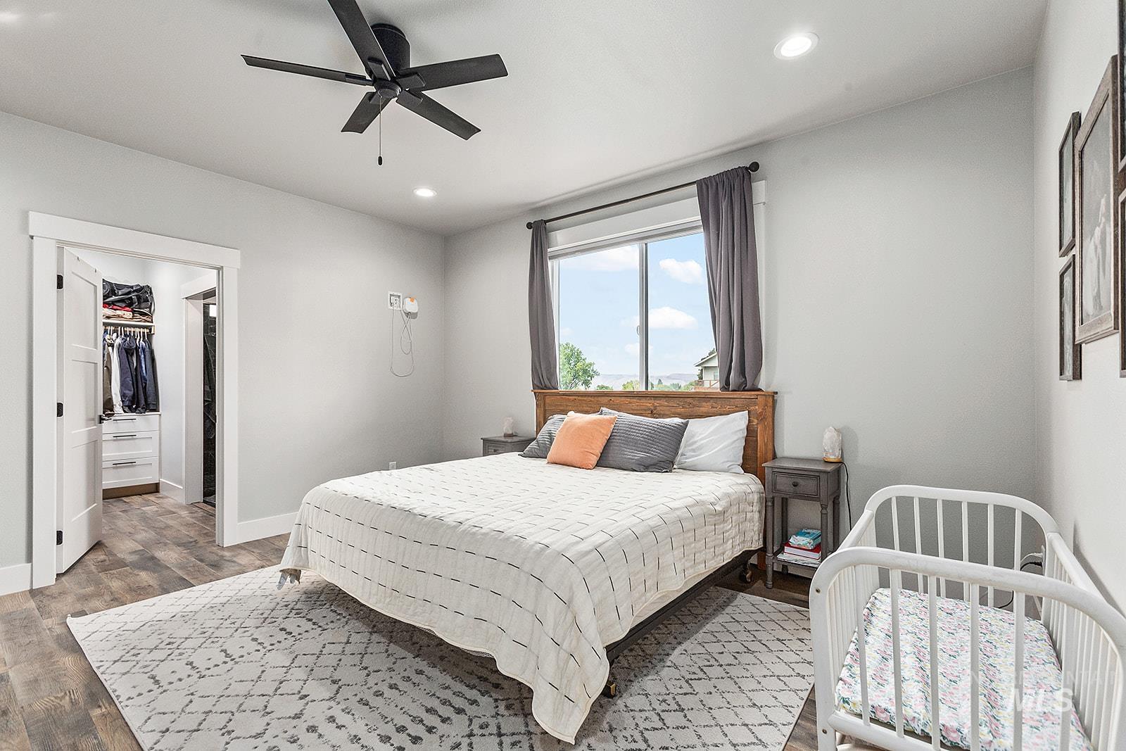 Bedroom with a walk in closet, wood finished floors, recessed lighting, and ceiling fan