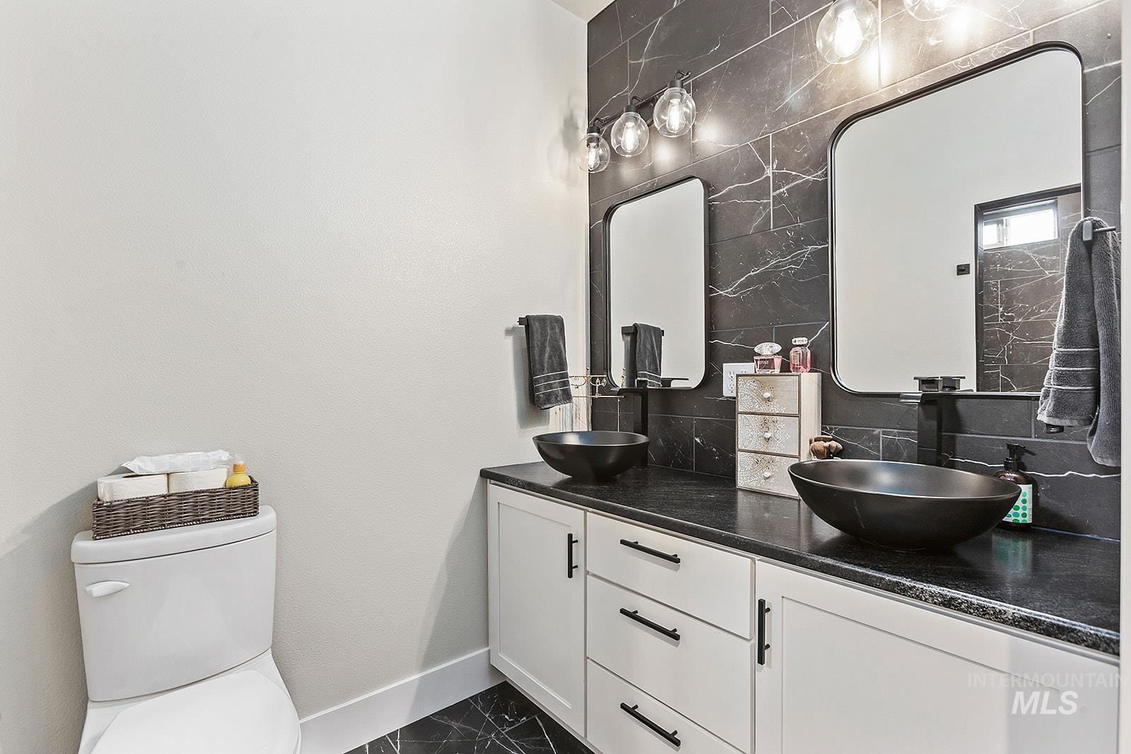 Bathroom featuring double vanity and backsplash