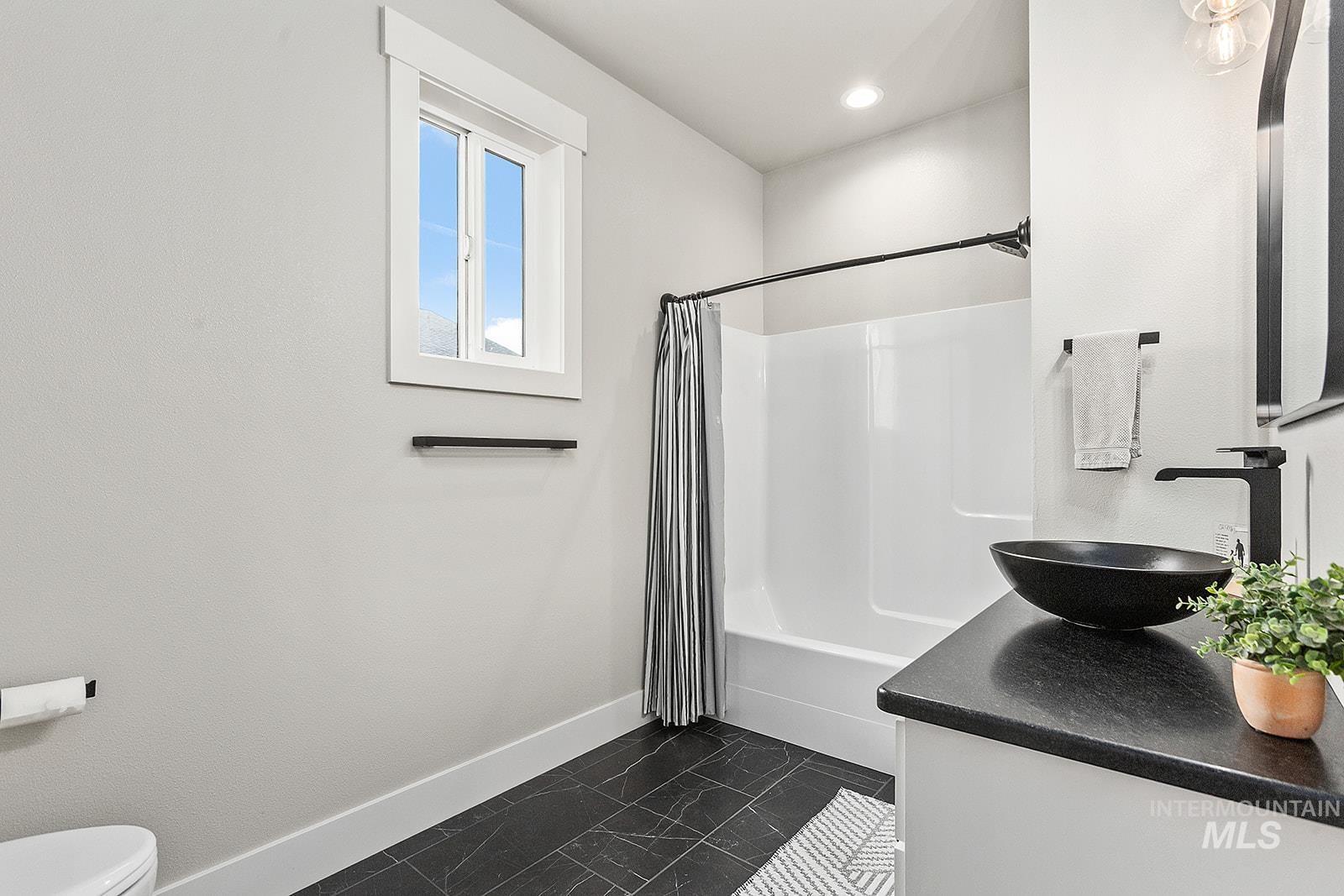 Full bath with shower / bathtub combination with curtain, vanity, and dark marble finish floors