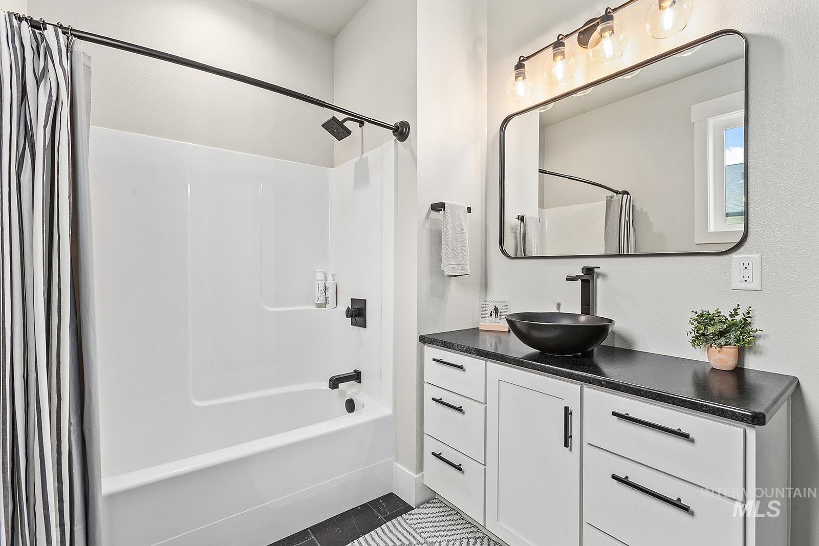 Full bath featuring shower / bath combo with shower curtain, vanity, and dark tile patterned flooring