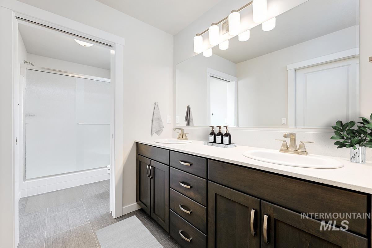 Bathroom with double vanity, a stall shower, and light tile patterned floors