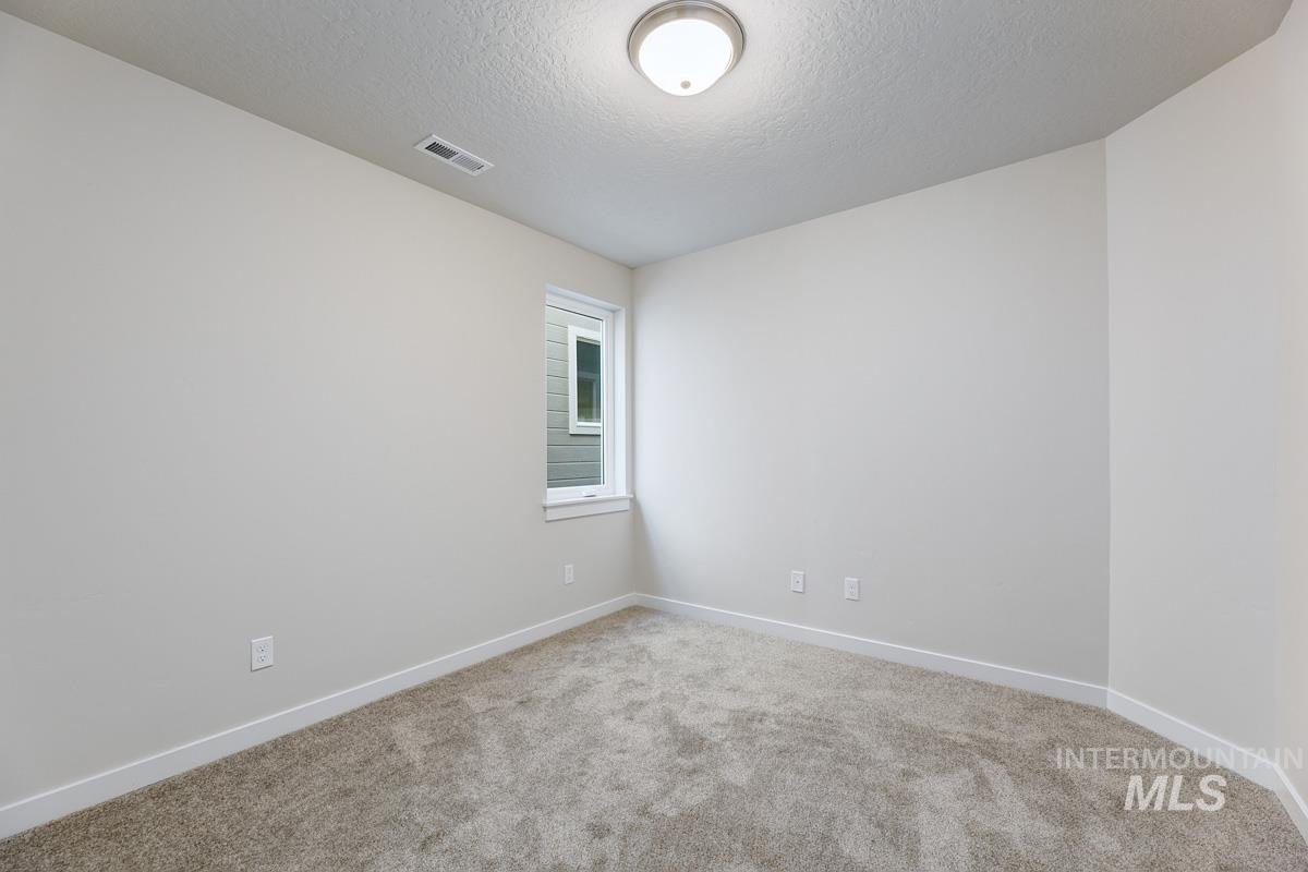 Unfurnished room featuring light carpet and a textured ceiling