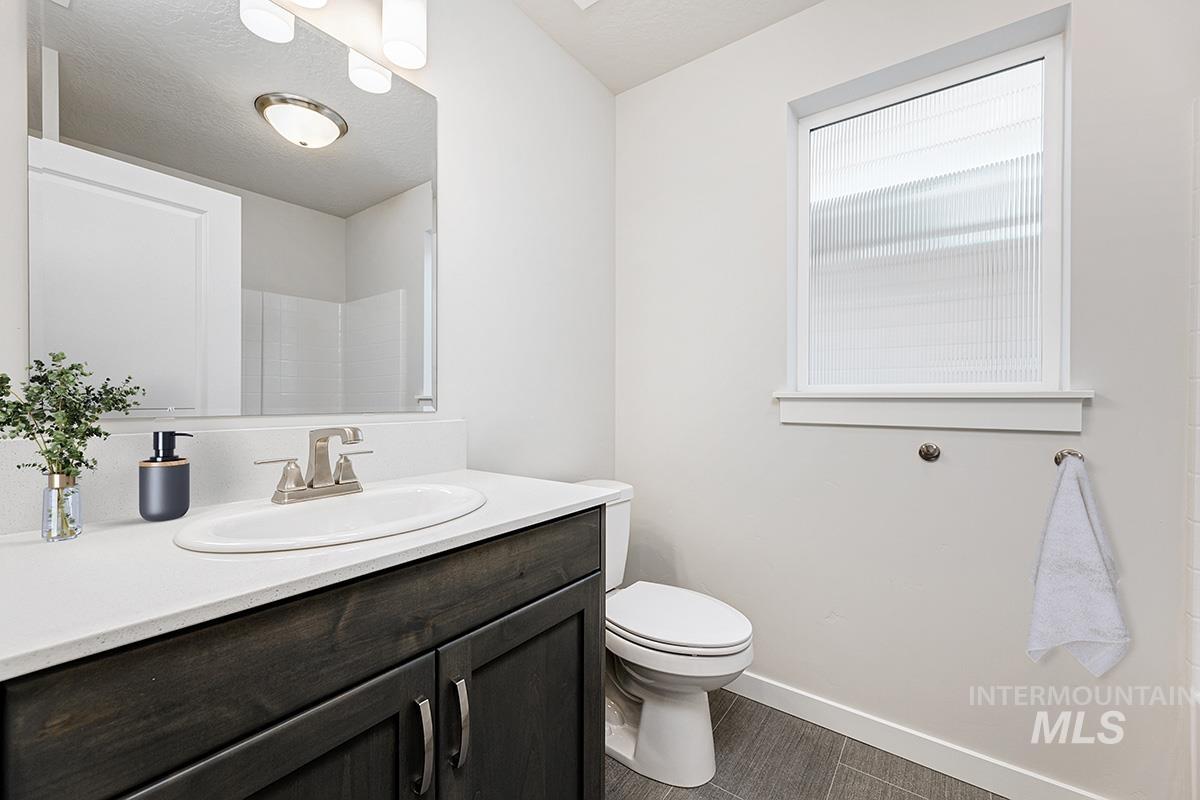 Full bathroom featuring vanity, a textured ceiling, dark tile patterned floors, and a shower
