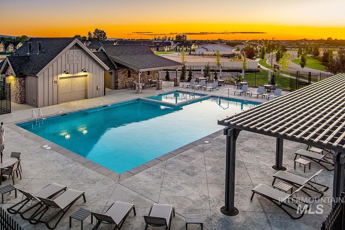 Pool at dusk with a patio, a pergola, and a pool with connected hot tub