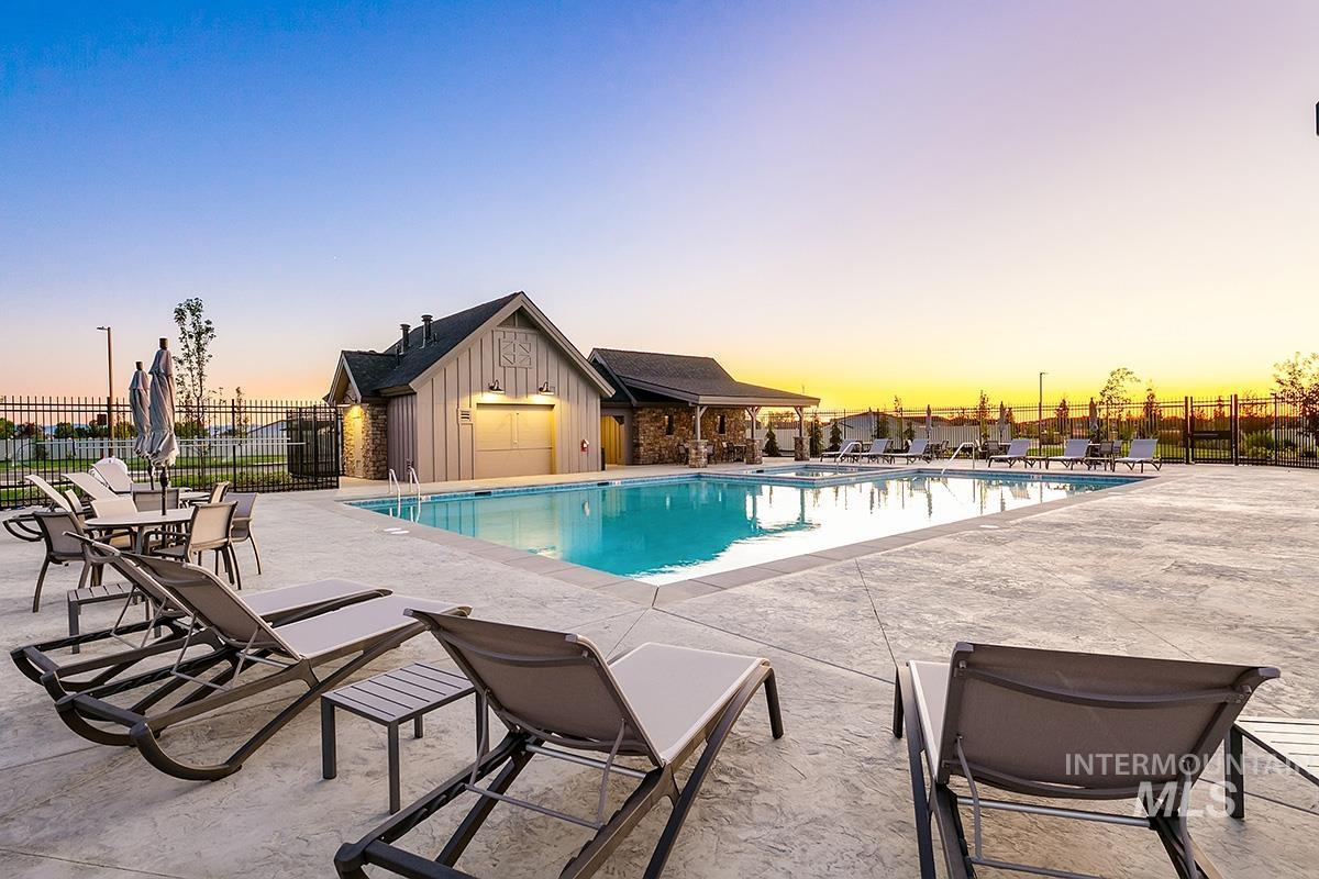 Pool at dusk featuring a patio area and a community pool