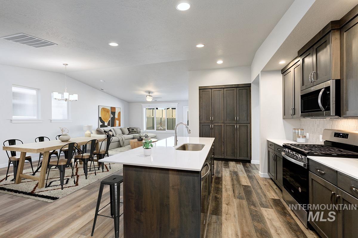 Kitchen featuring appliances with stainless steel finishes, dark wood finished floors, open floor plan, dark brown cabinets, and recessed lighting