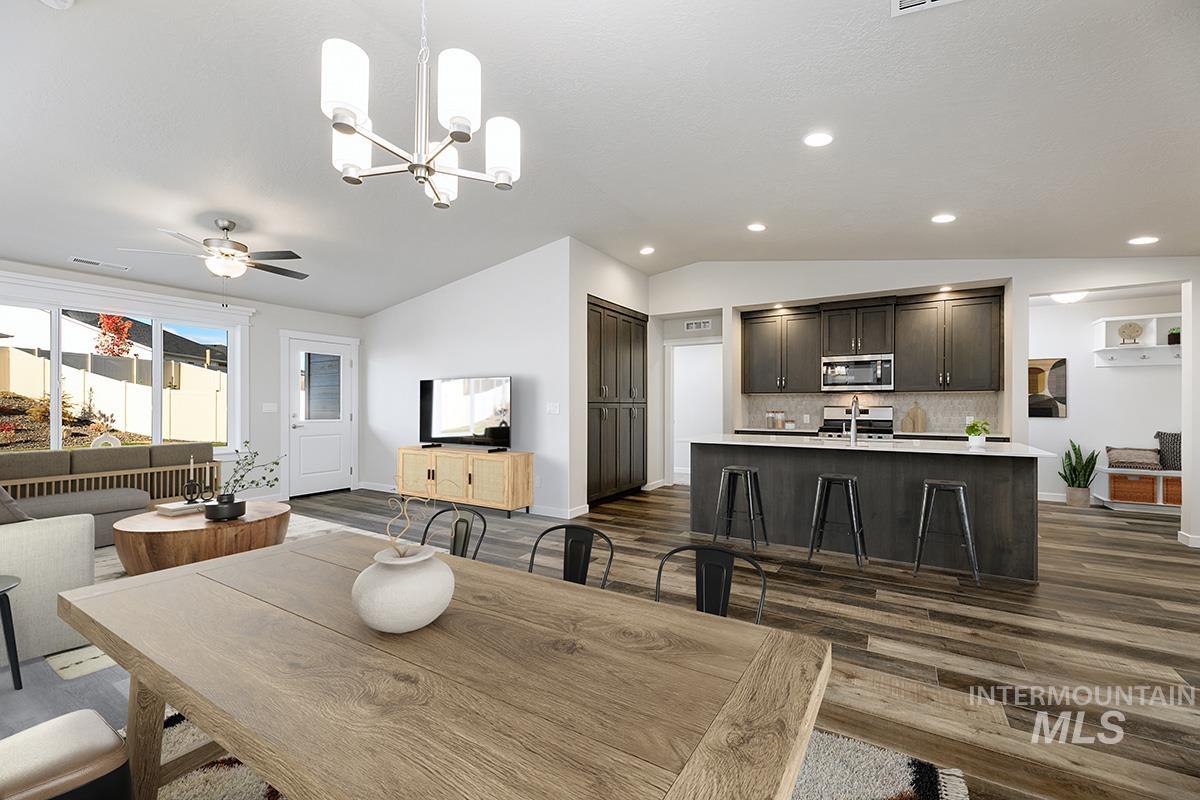 Dining room with vaulted ceiling, a chandelier, dark wood-style flooring, ceiling fan, and recessed lighting