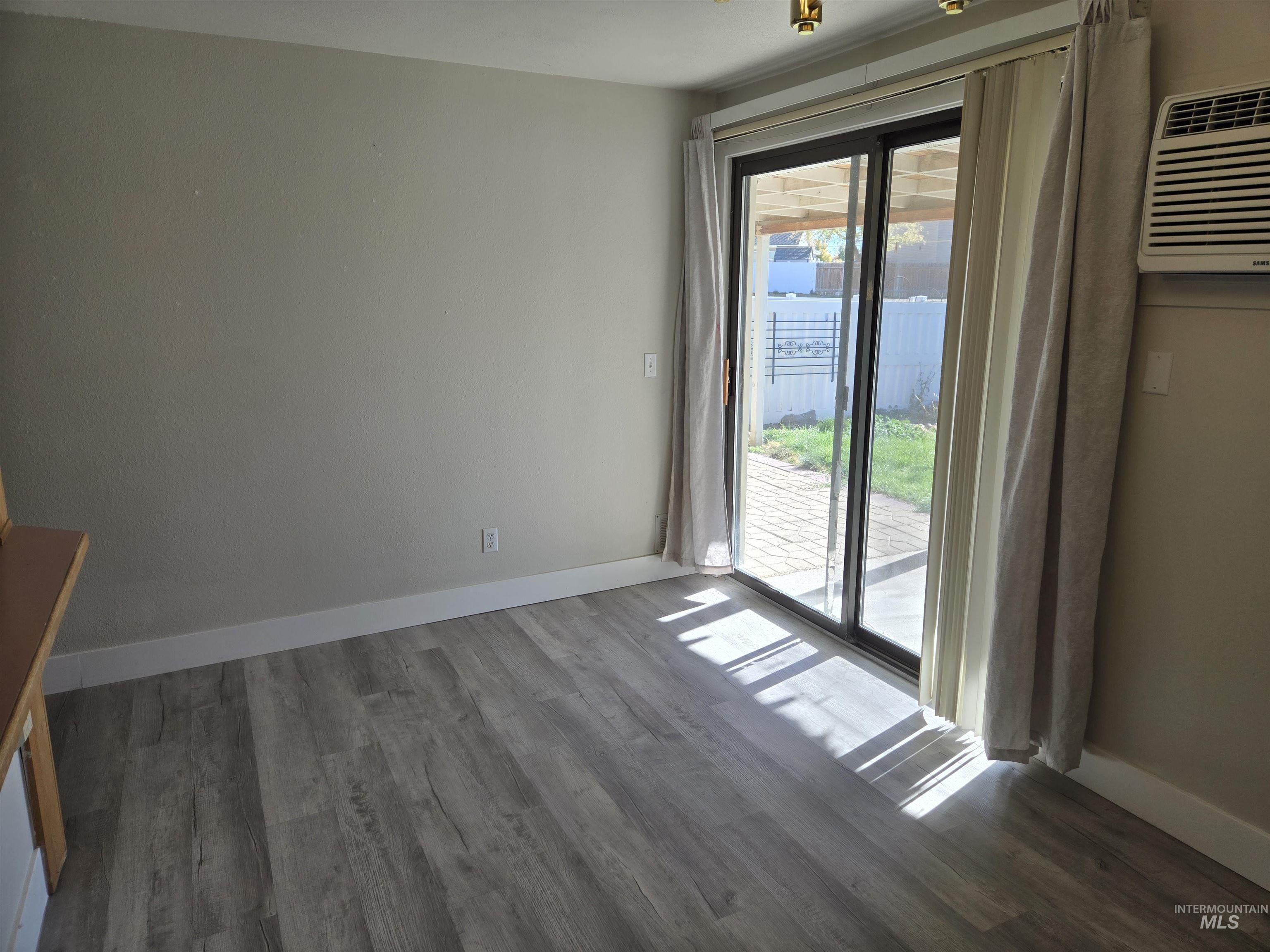 Unfurnished room featuring dark wood finished floors and an AC wall unit