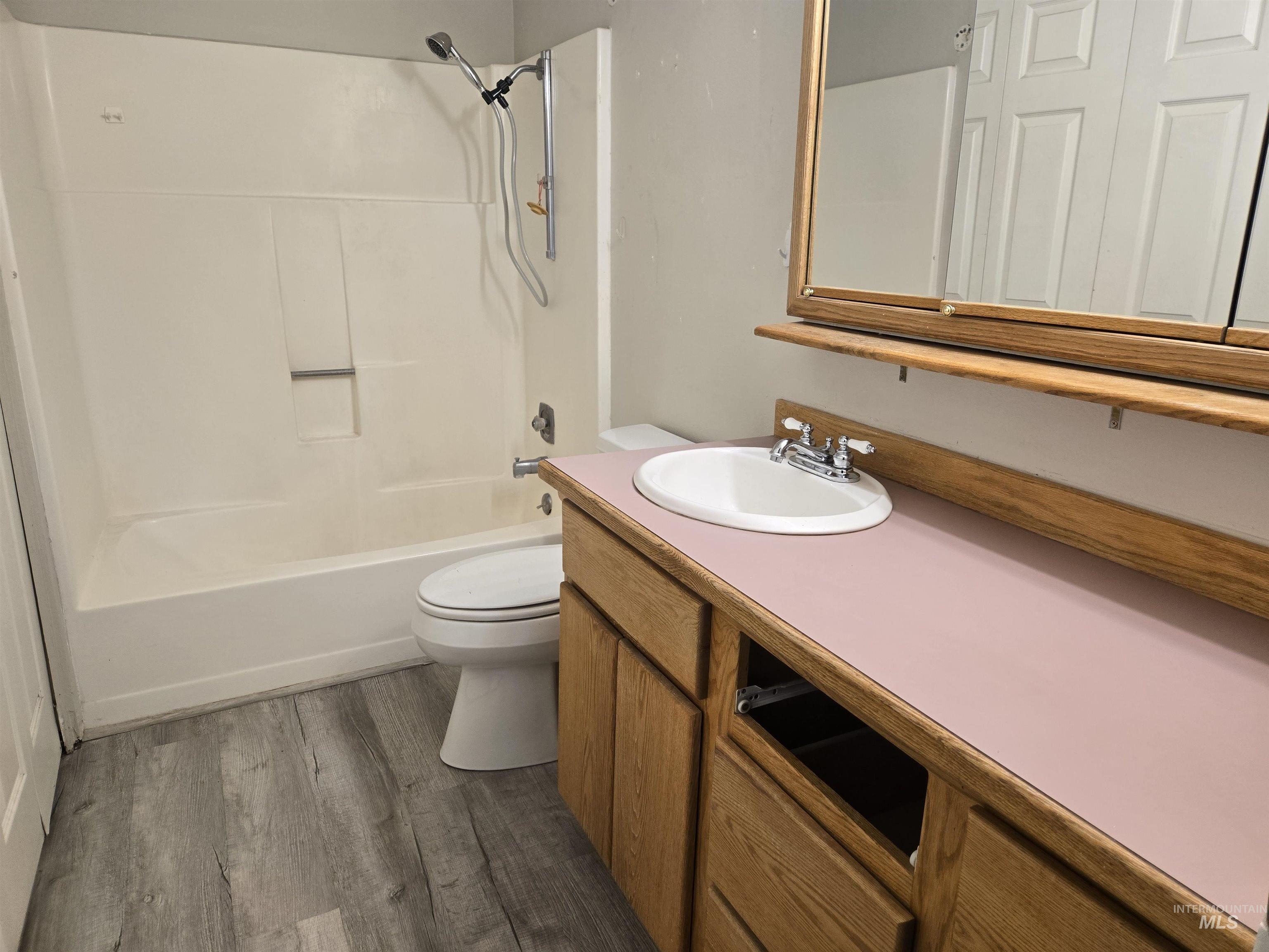 Bathroom featuring vanity, dark wood-style floors, and  shower combination