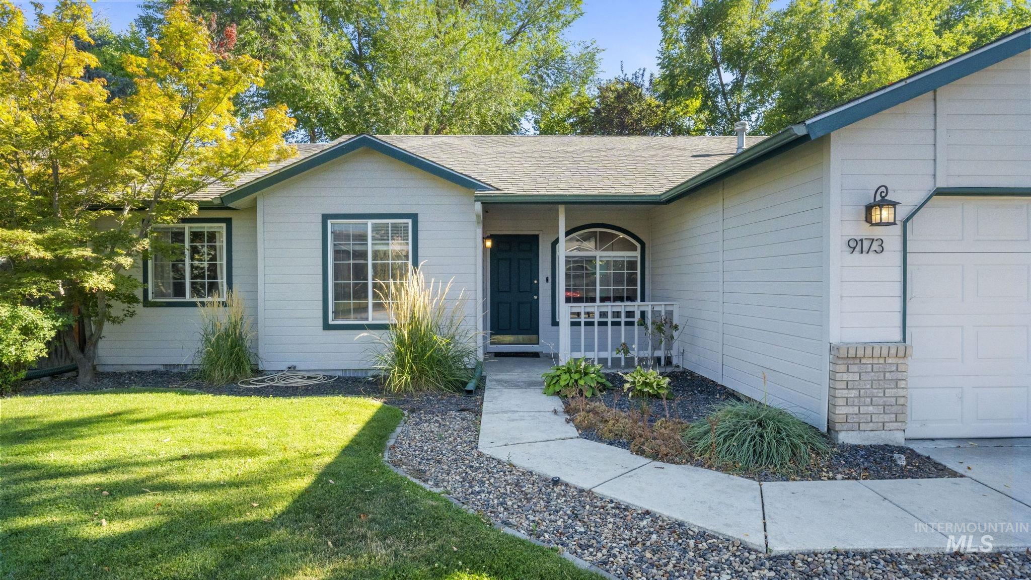 View of exterior entry featuring a garage, a yard, and a shingled roof