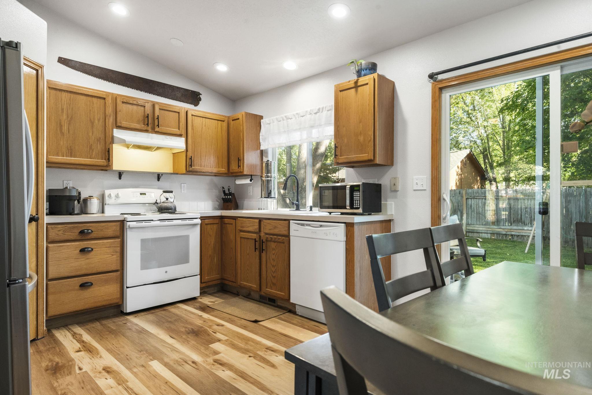 Kitchen with stainless steel appliances, brown cabinets, light countertops, light wood-style flooring, and recessed lighting