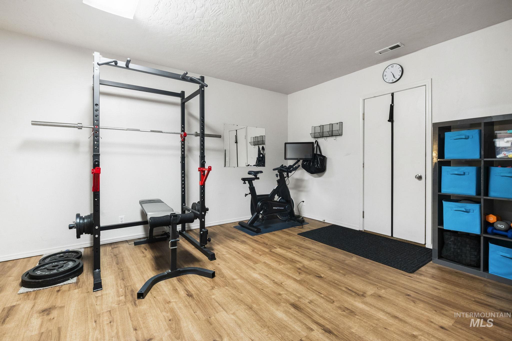 Workout area featuring a textured ceiling and light wood-type flooring
