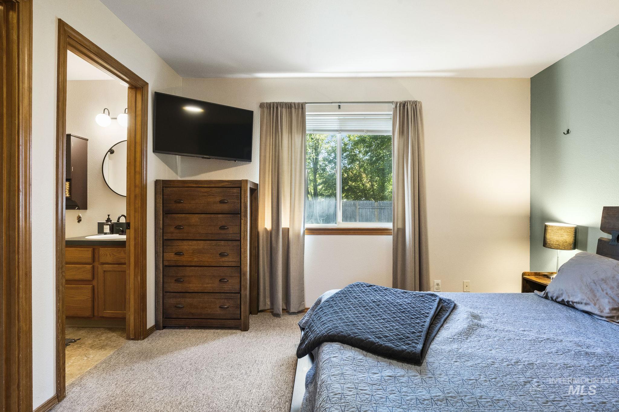 Bedroom with light colored carpet and connected bathroom