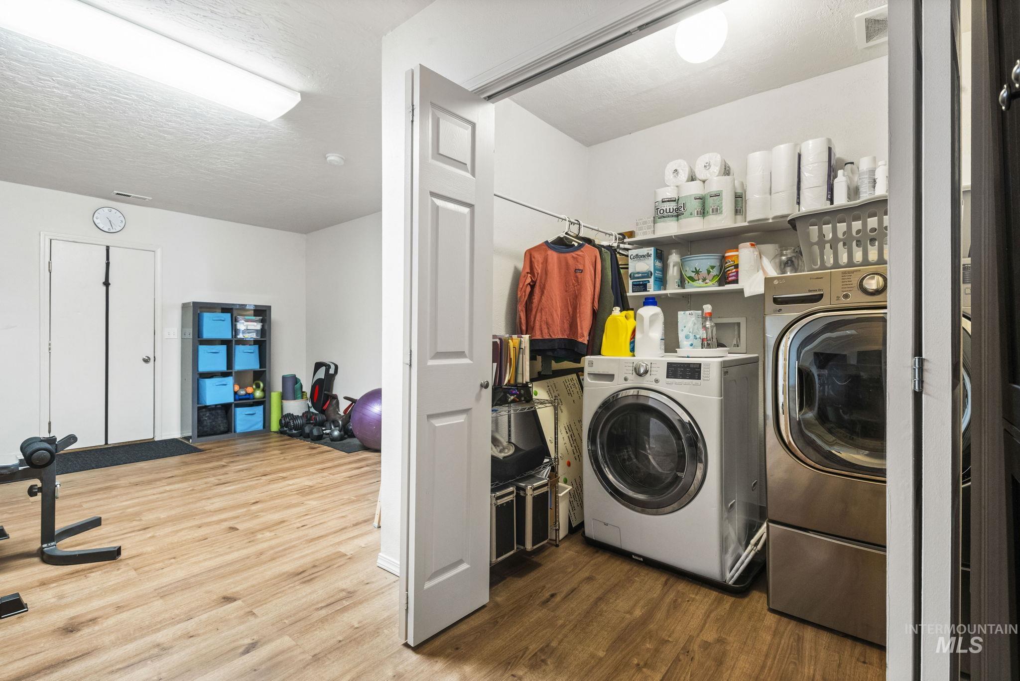 Washroom with wood finished floors, a textured ceiling, and washing machine and dryer