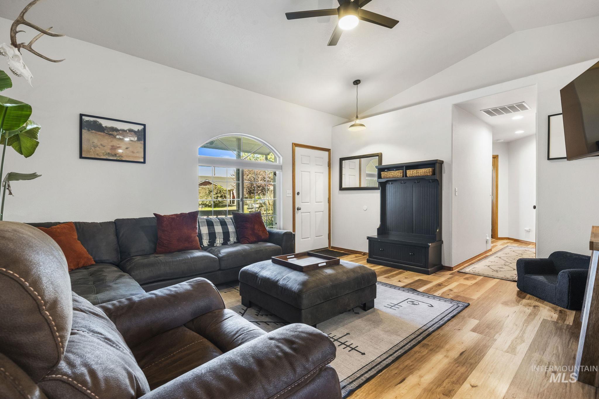 Living room featuring lofted ceiling, wood finished floors, and ceiling fan
