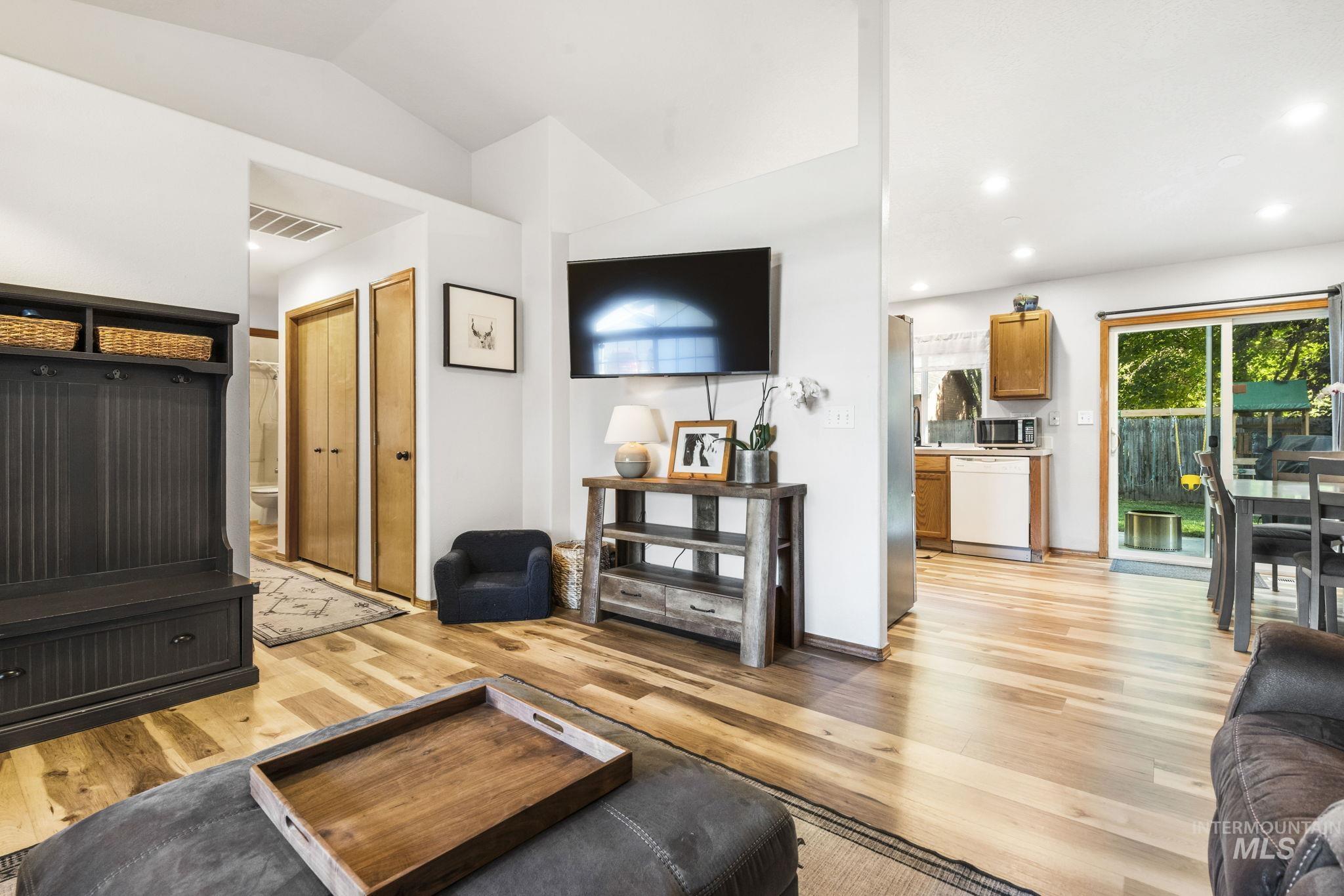 Living room featuring light wood-type flooring, recessed lighting, and vaulted ceiling