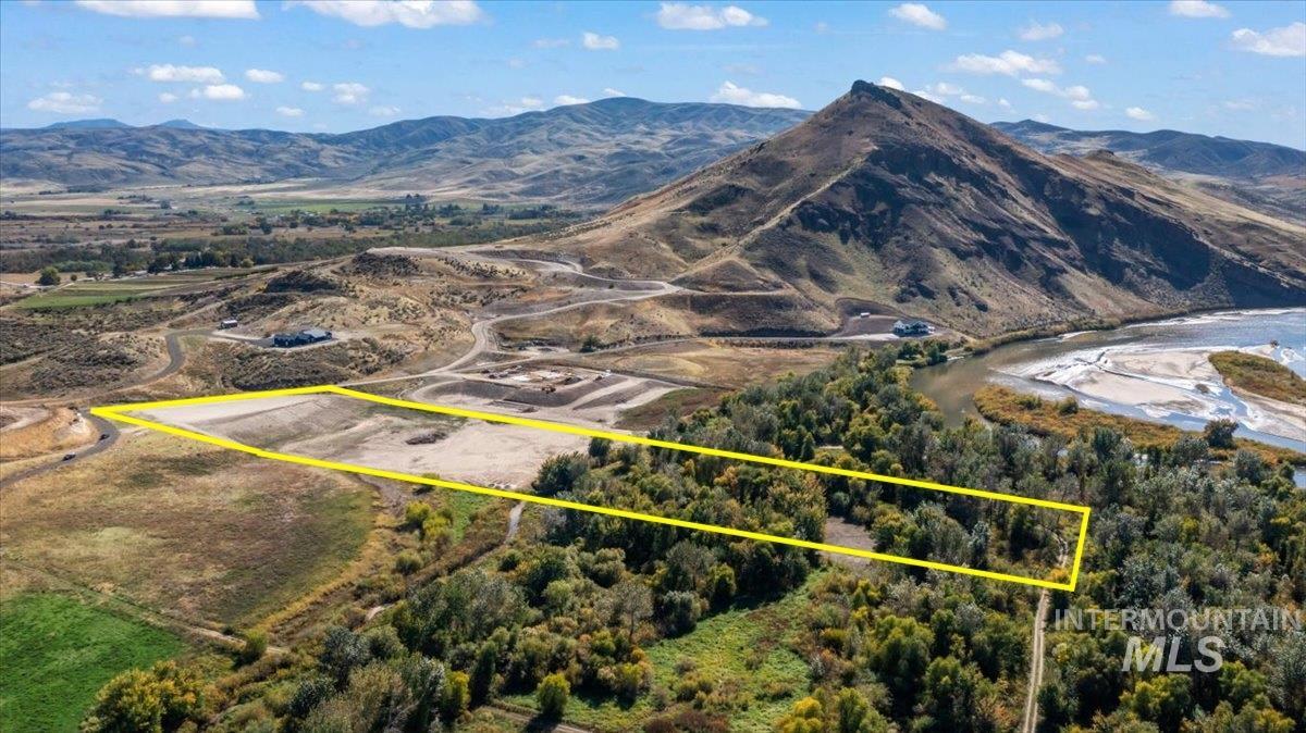 Aerial view of property and surrounding area with property parcel outlined and a mountainous background