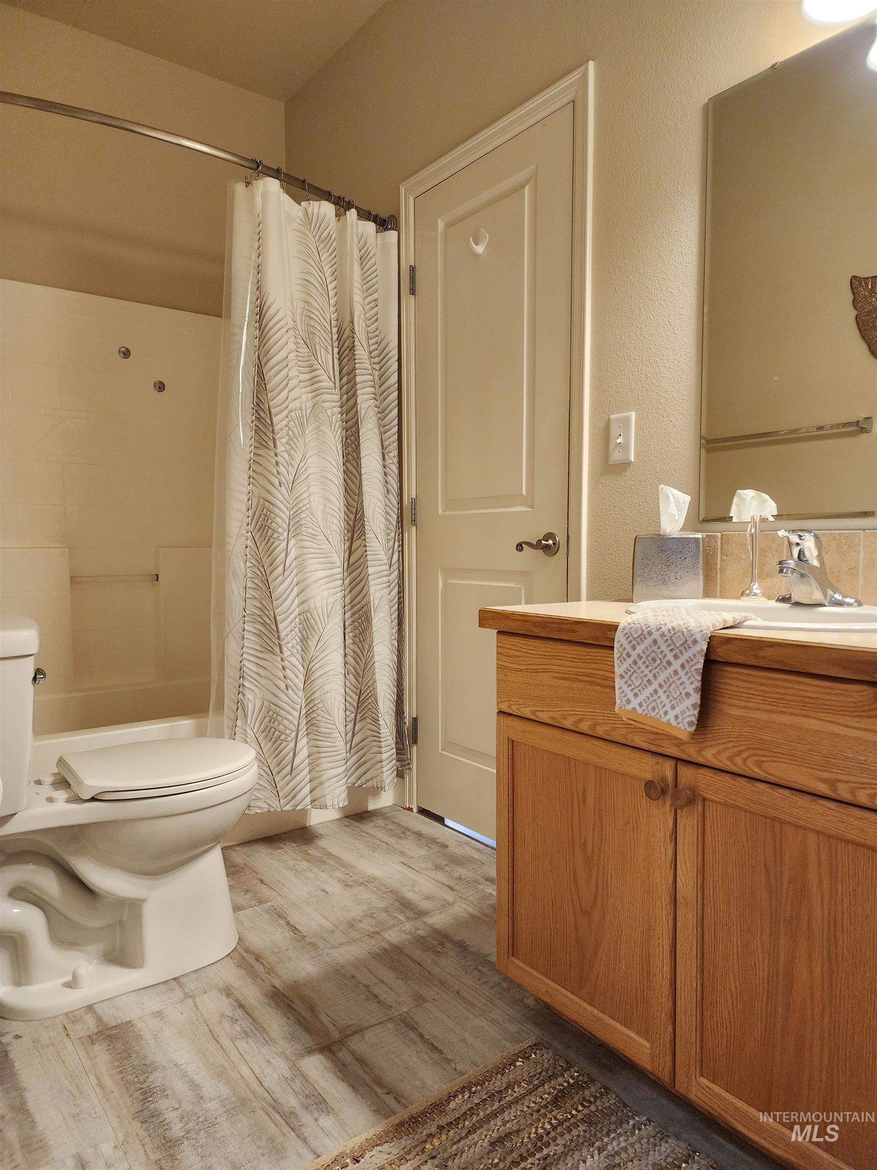 Full bathroom with vanity, light wood-style flooring, and shower / bath combination with curtain