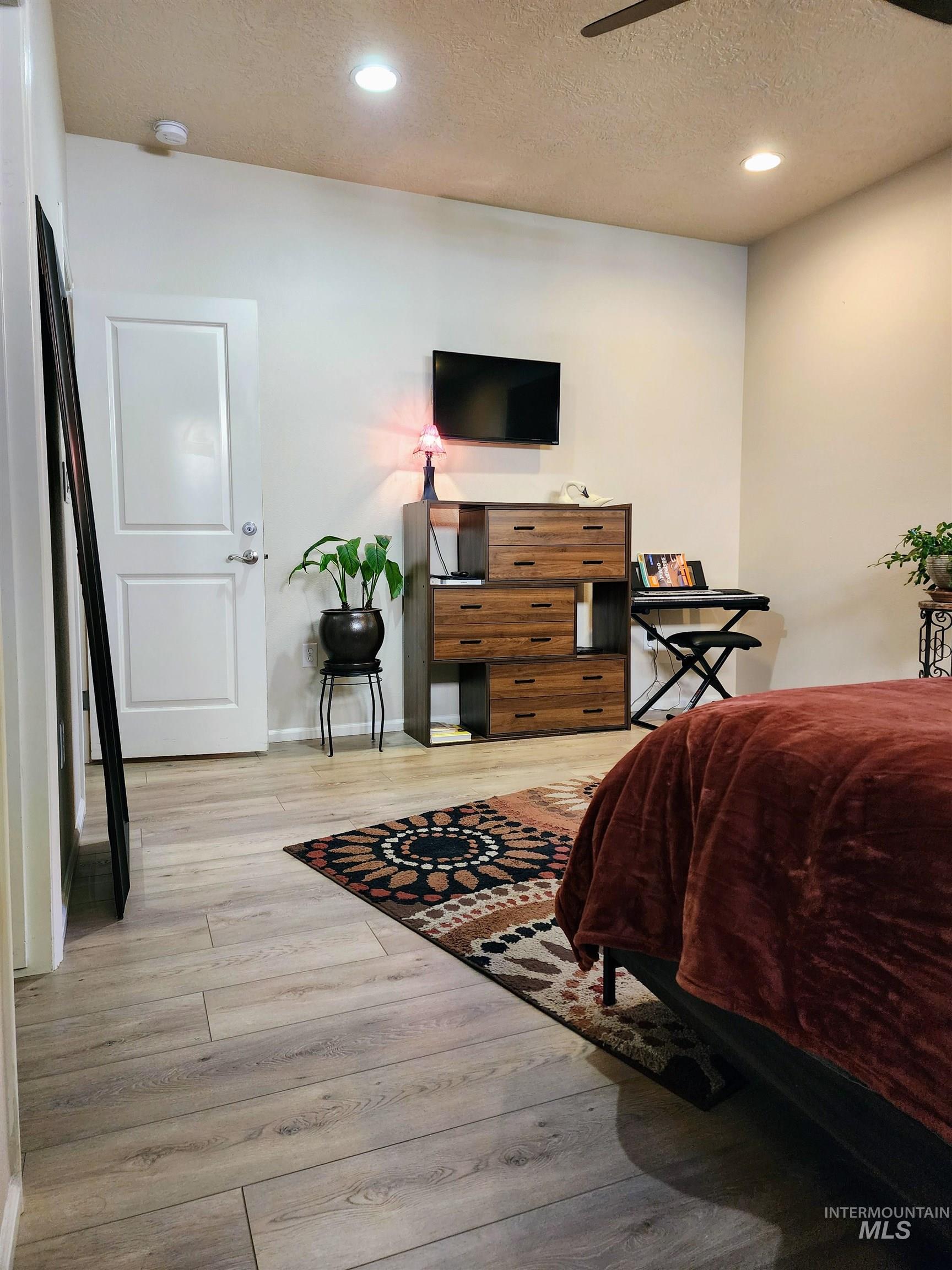 Bedroom featuring a textured ceiling, light wood finished floors, recessed lighting, and ceiling fan