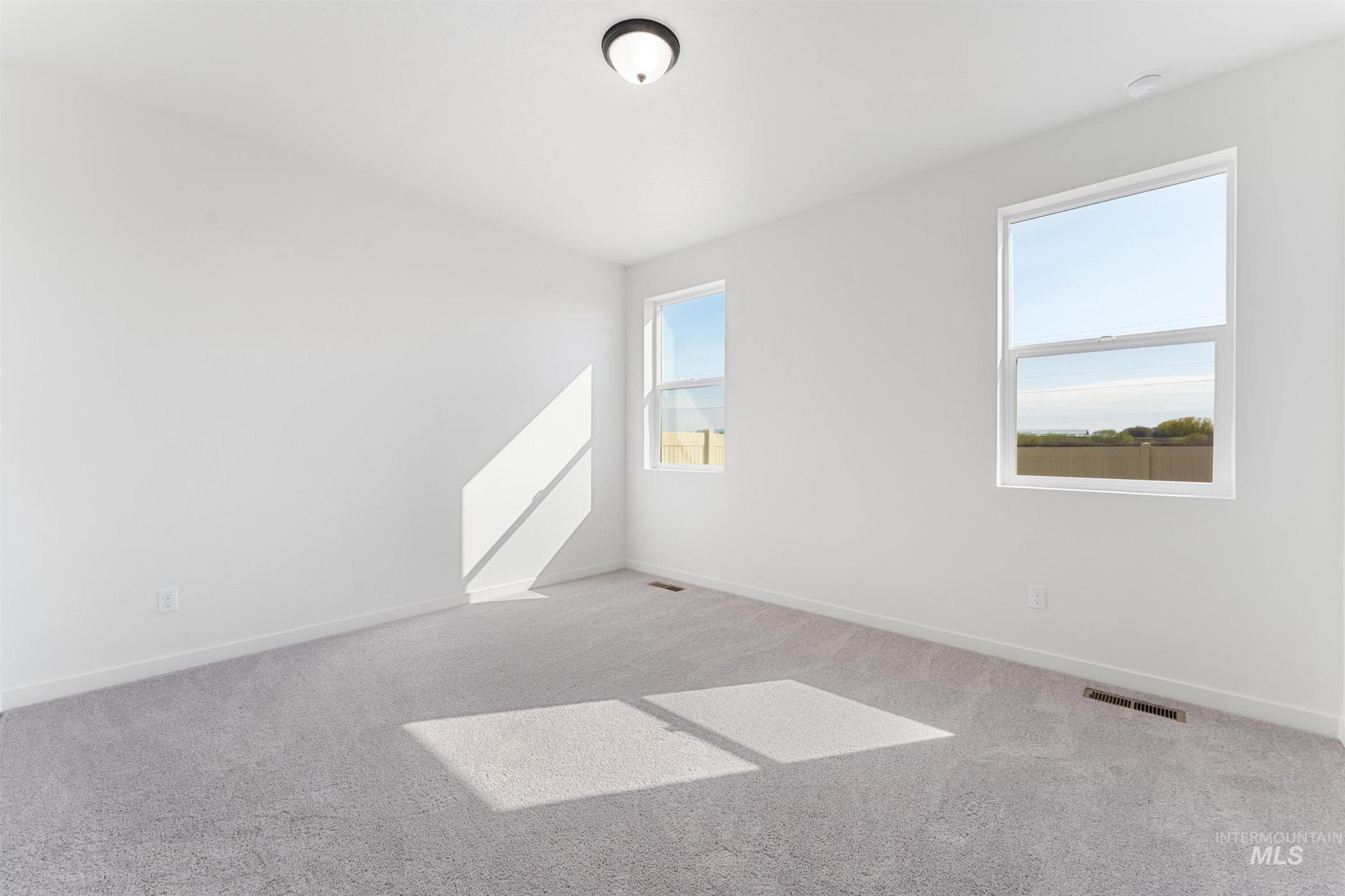 Empty room with light colored carpet and baseboards
