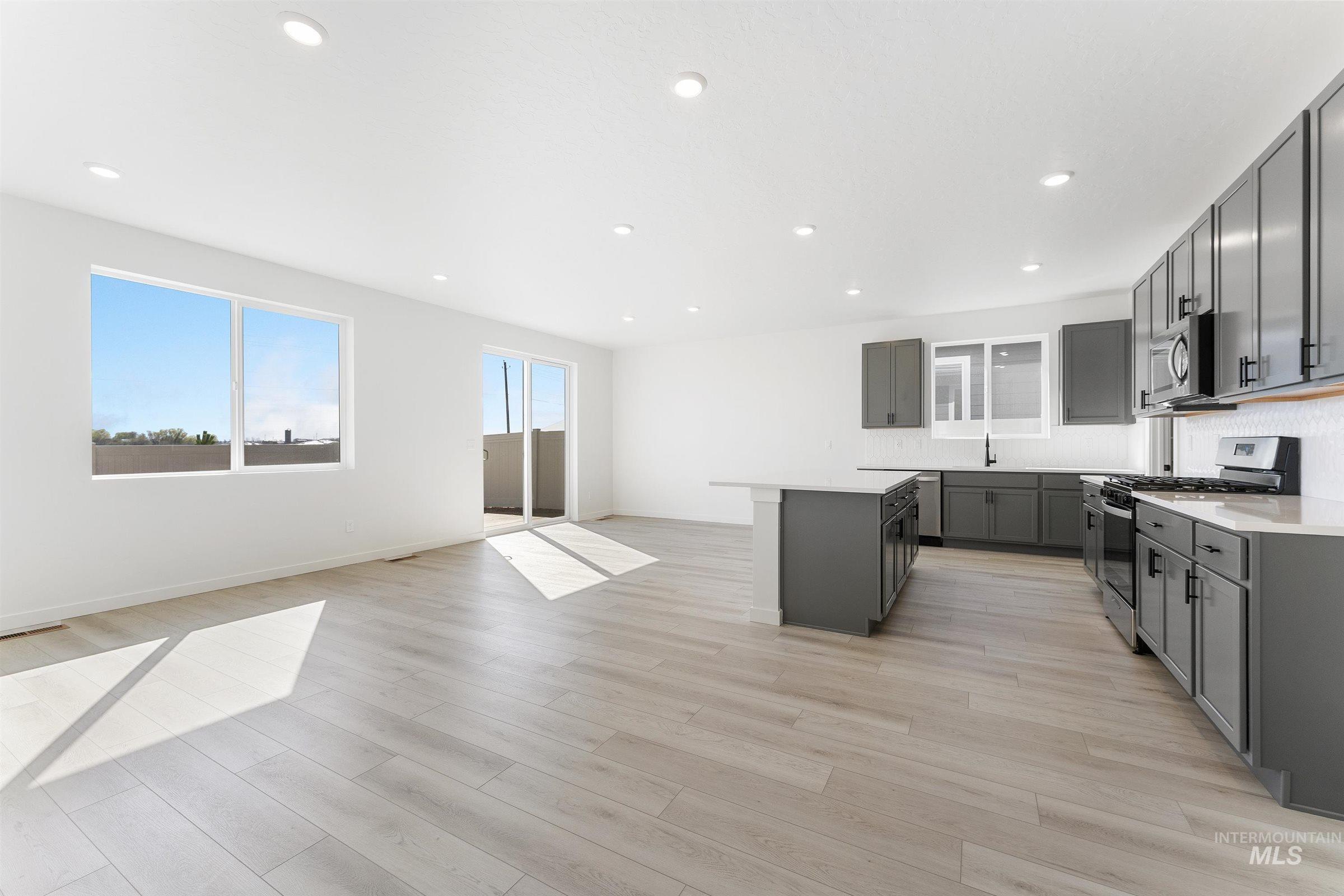 Kitchen featuring stainless steel appliances, a center island, recessed lighting, light wood-type flooring, and open floor plan