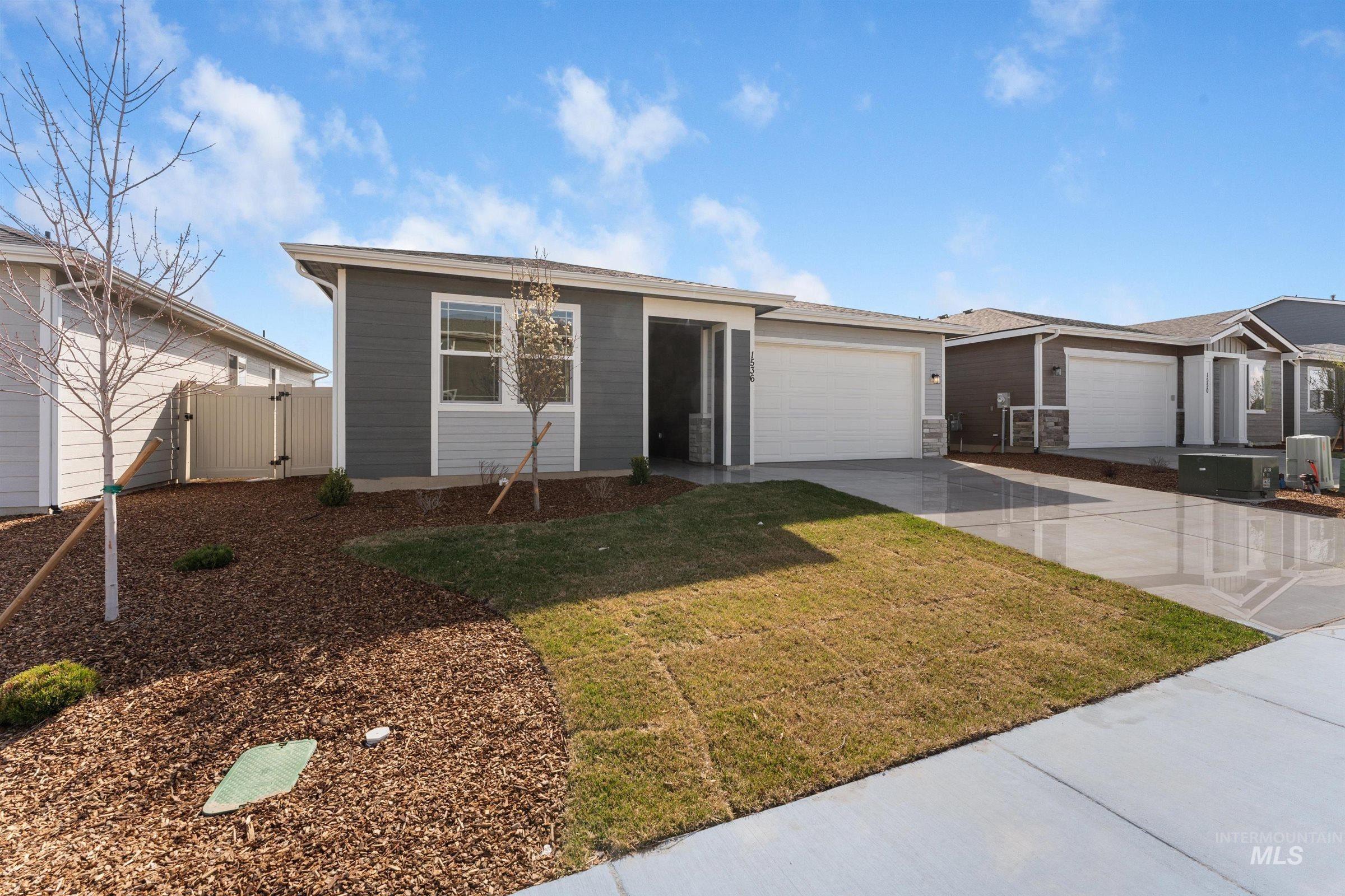 View of front of house with driveway, an attached garage, and a gate