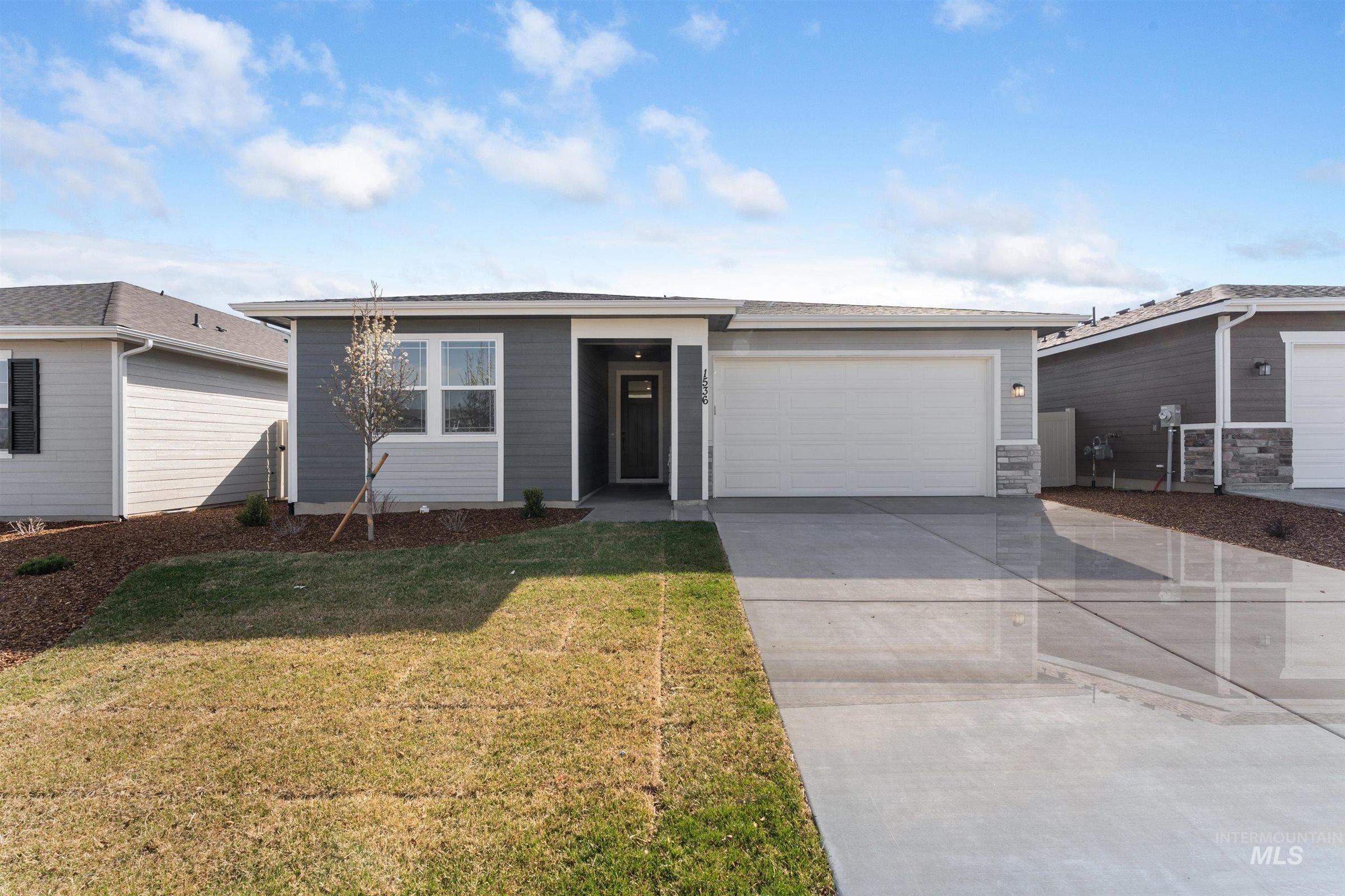 View of front facade featuring driveway, a front yard, and a garage