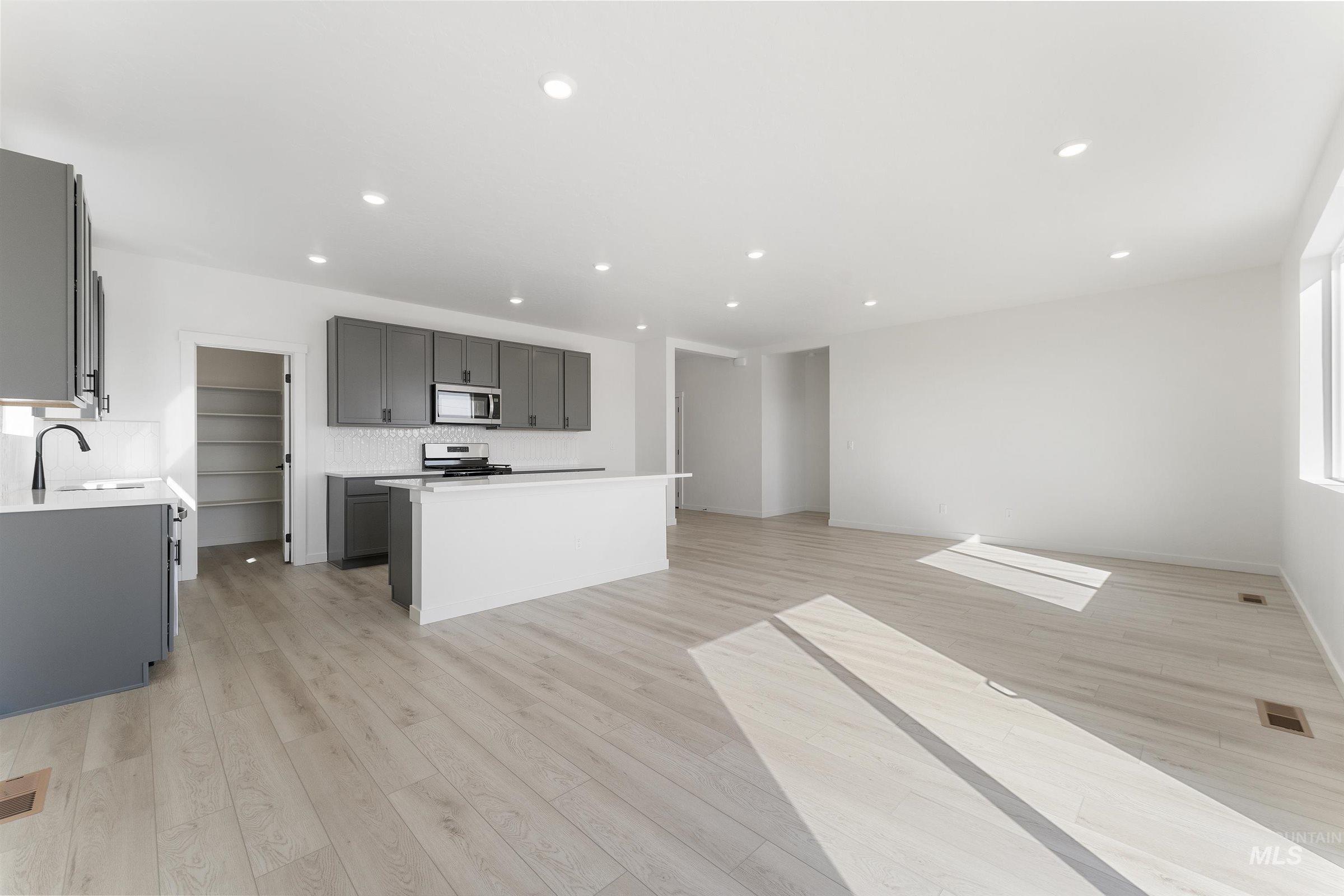 Kitchen featuring gray cabinetry, light wood-style floors, open floor plan, backsplash, and recessed lighting