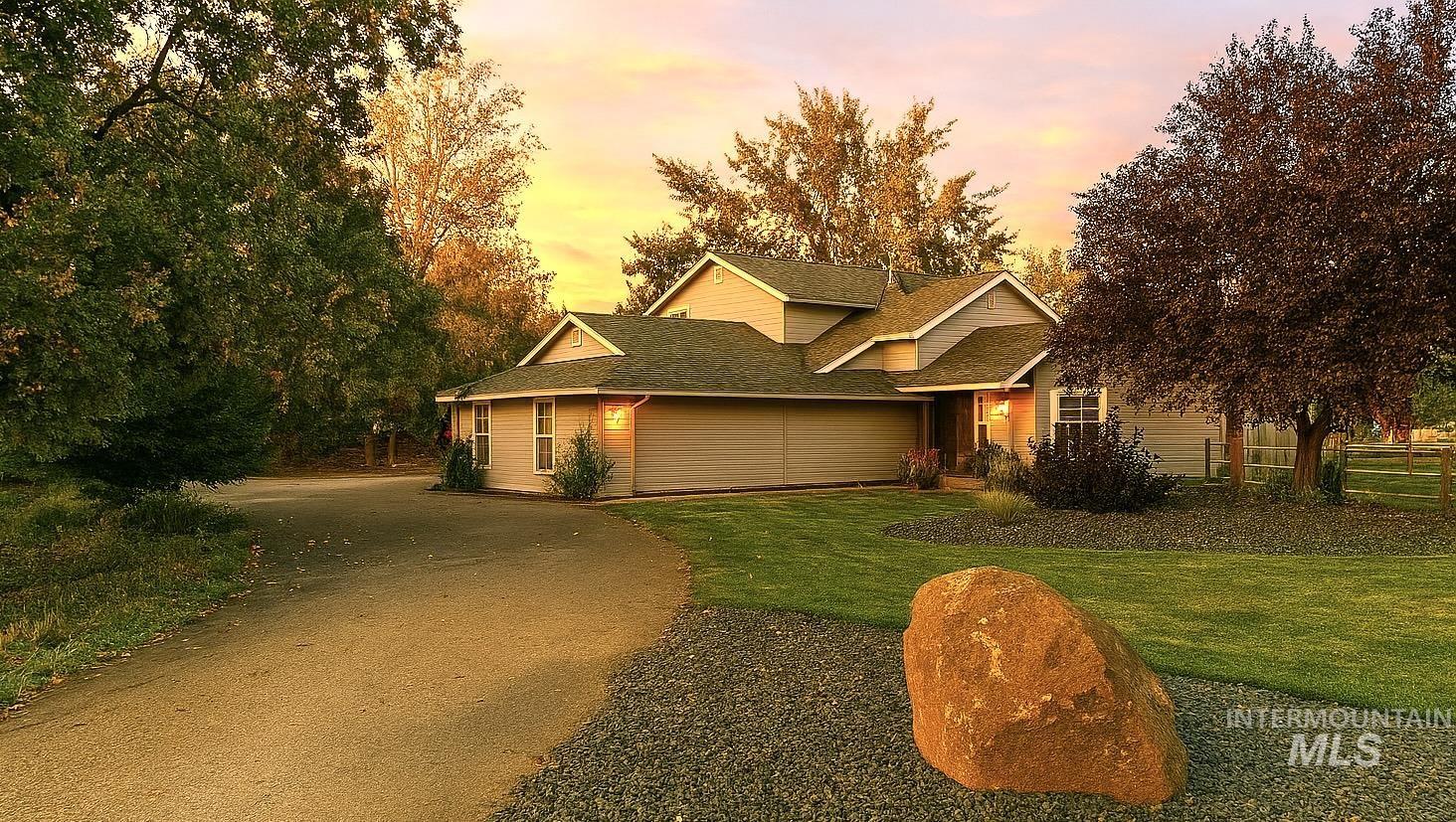 View of front facade featuring a shingled roof, driveway, and a front yard