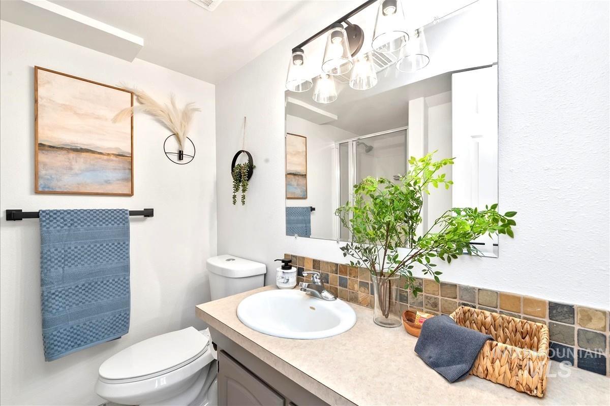 Bathroom with tasteful backsplash, vanity, a stall shower, and a chandelier
