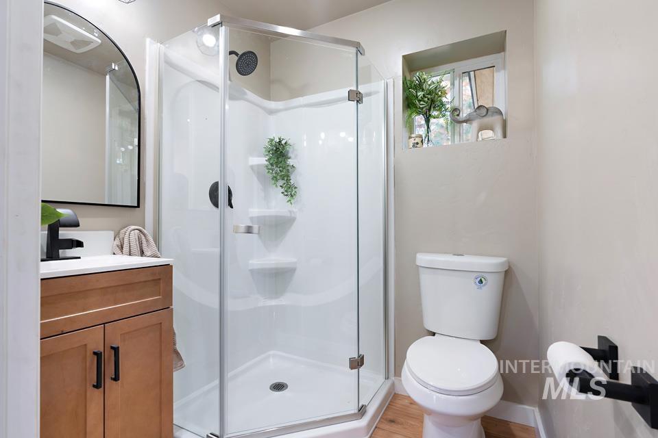 Full bathroom with a stall shower, vanity, and light wood-type flooring