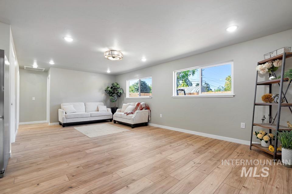 Living area with light wood finished floors and recessed lighting