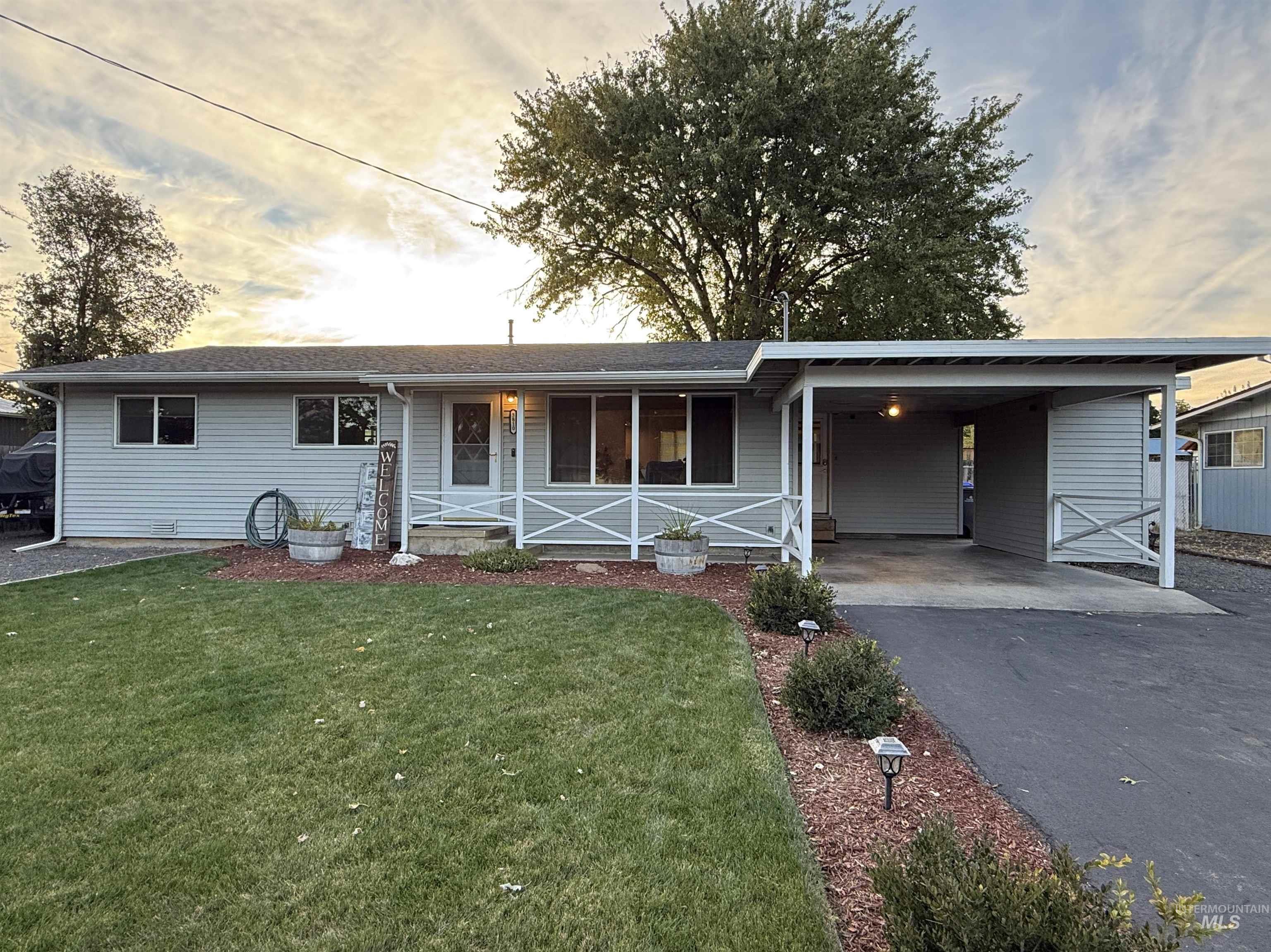Ranch-style home featuring a front yard, an attached carport, and asphalt driveway